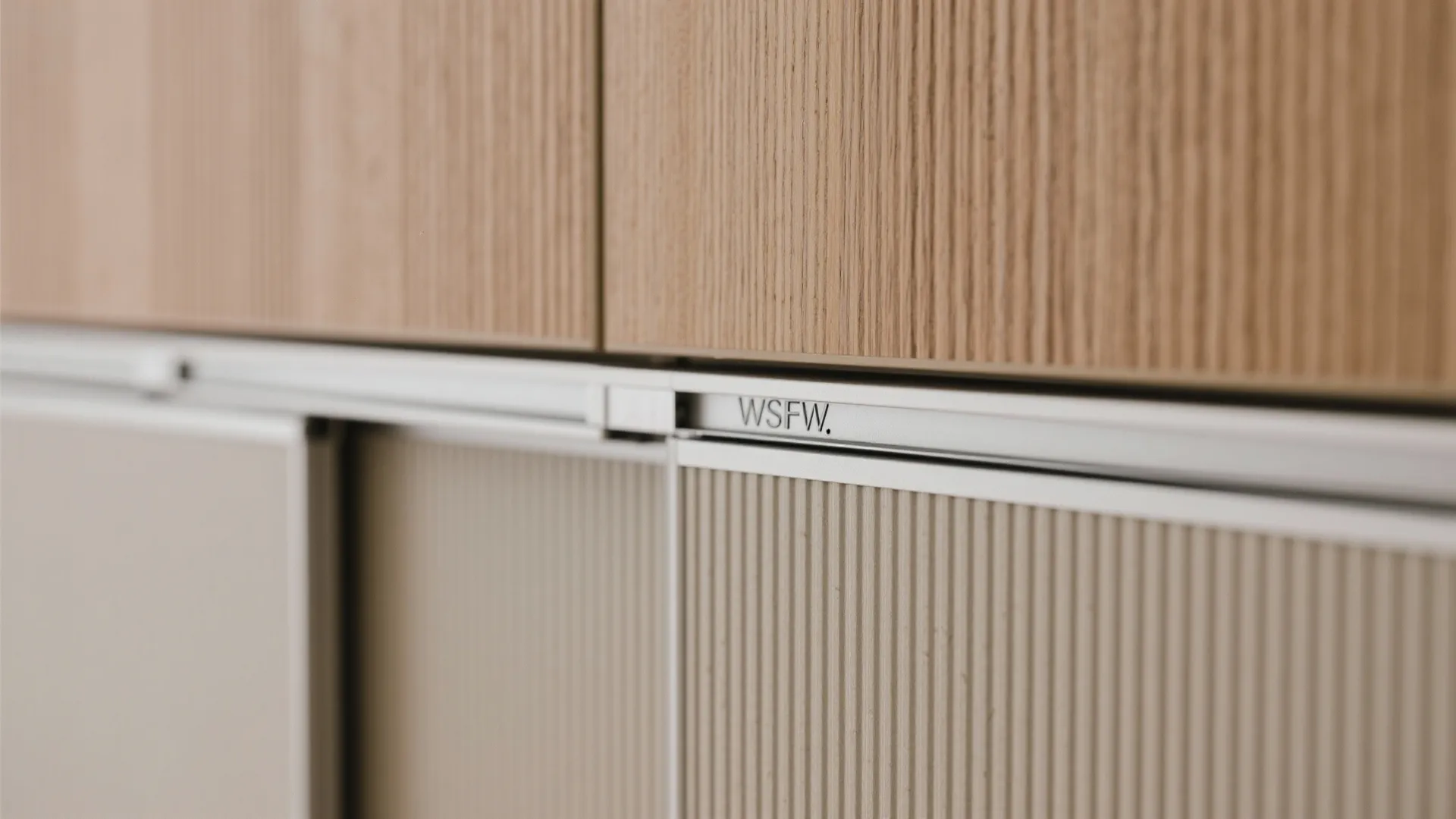 Close up view of wooden cabinet door panel with metal sliding track and vertical line texture