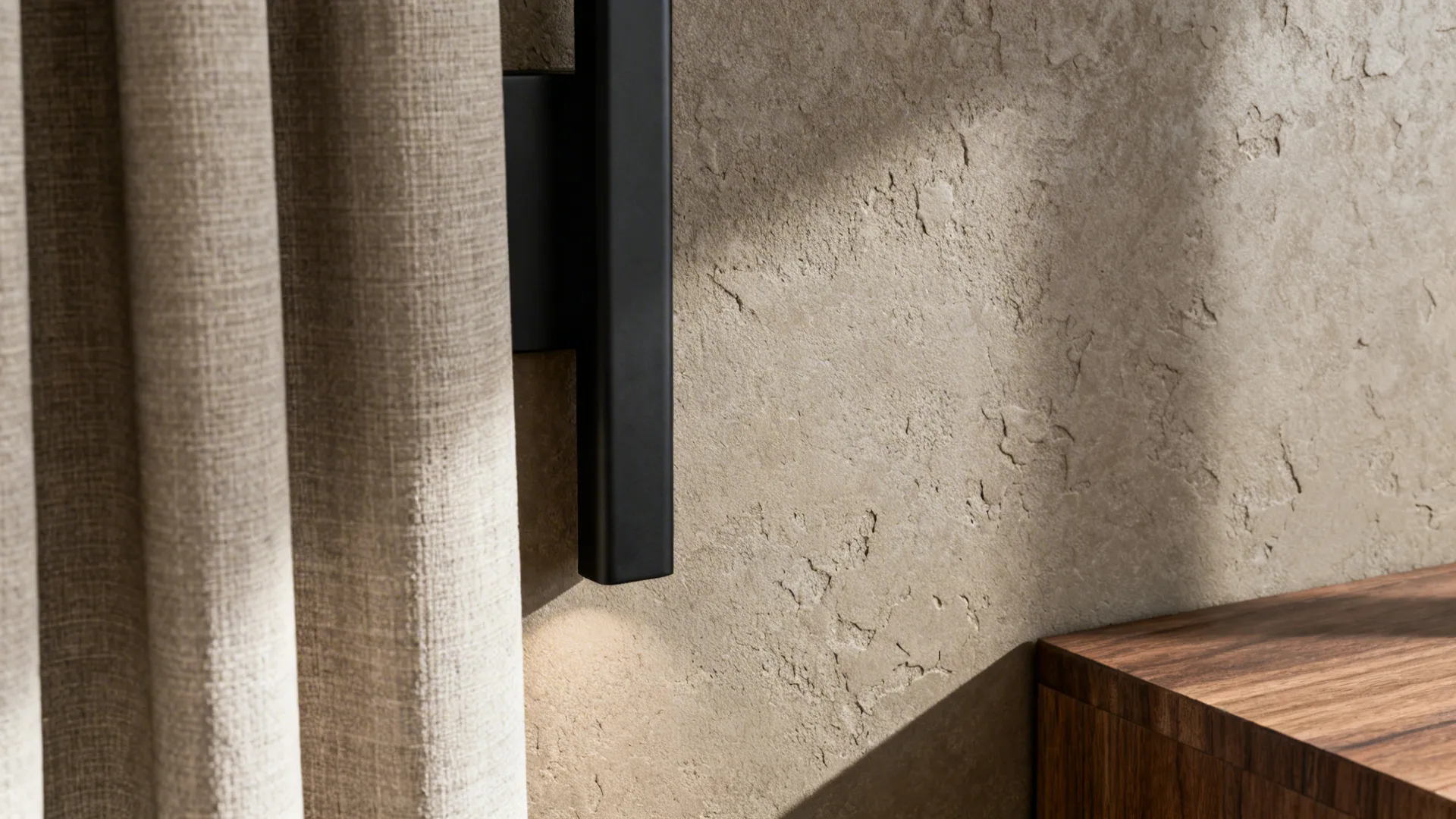Macro view of taupe stucco wall with stone-like texture beside linen and wood.