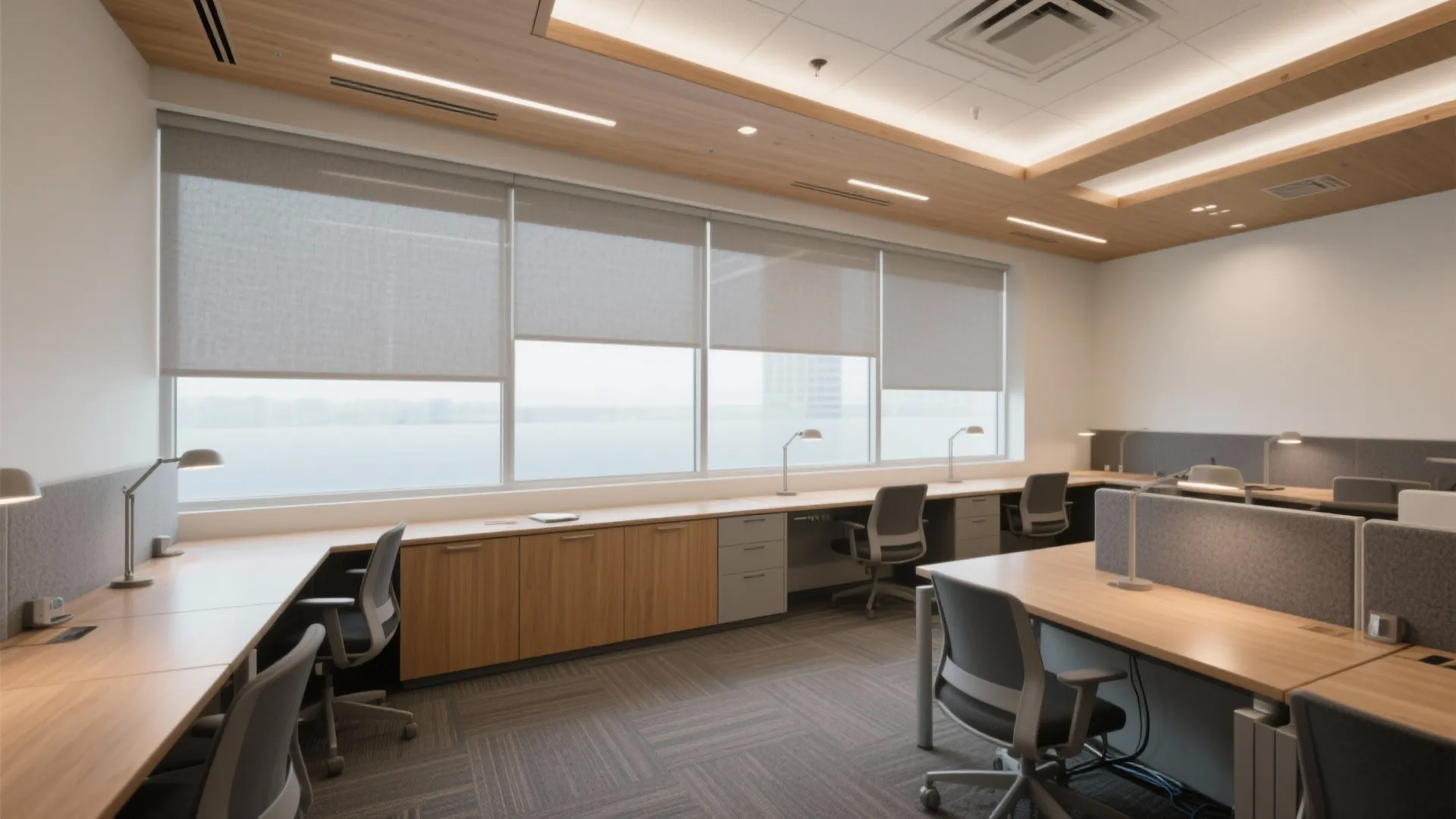 Spacious office study area with long wooden desks grey chairs large windows and bright ceiling