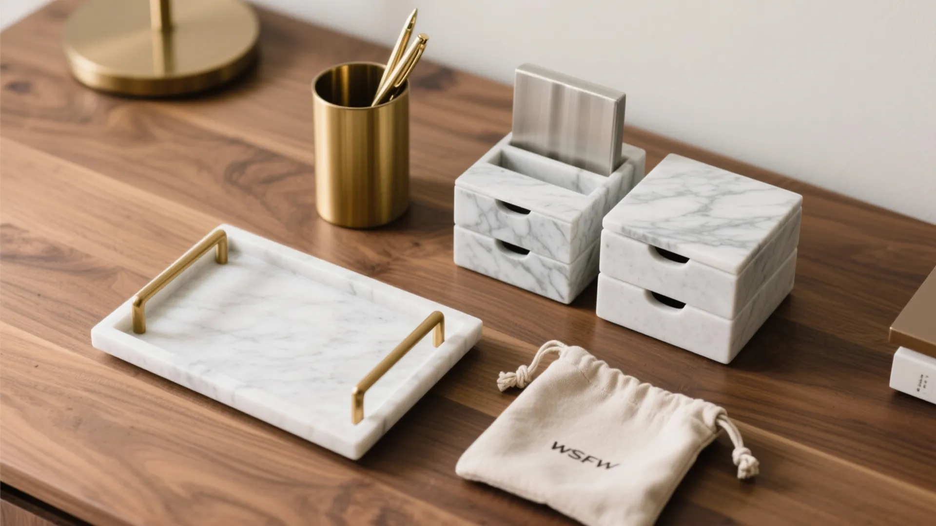 Marble tray with gold handles on wood desk beside small marble drawers and gold cup