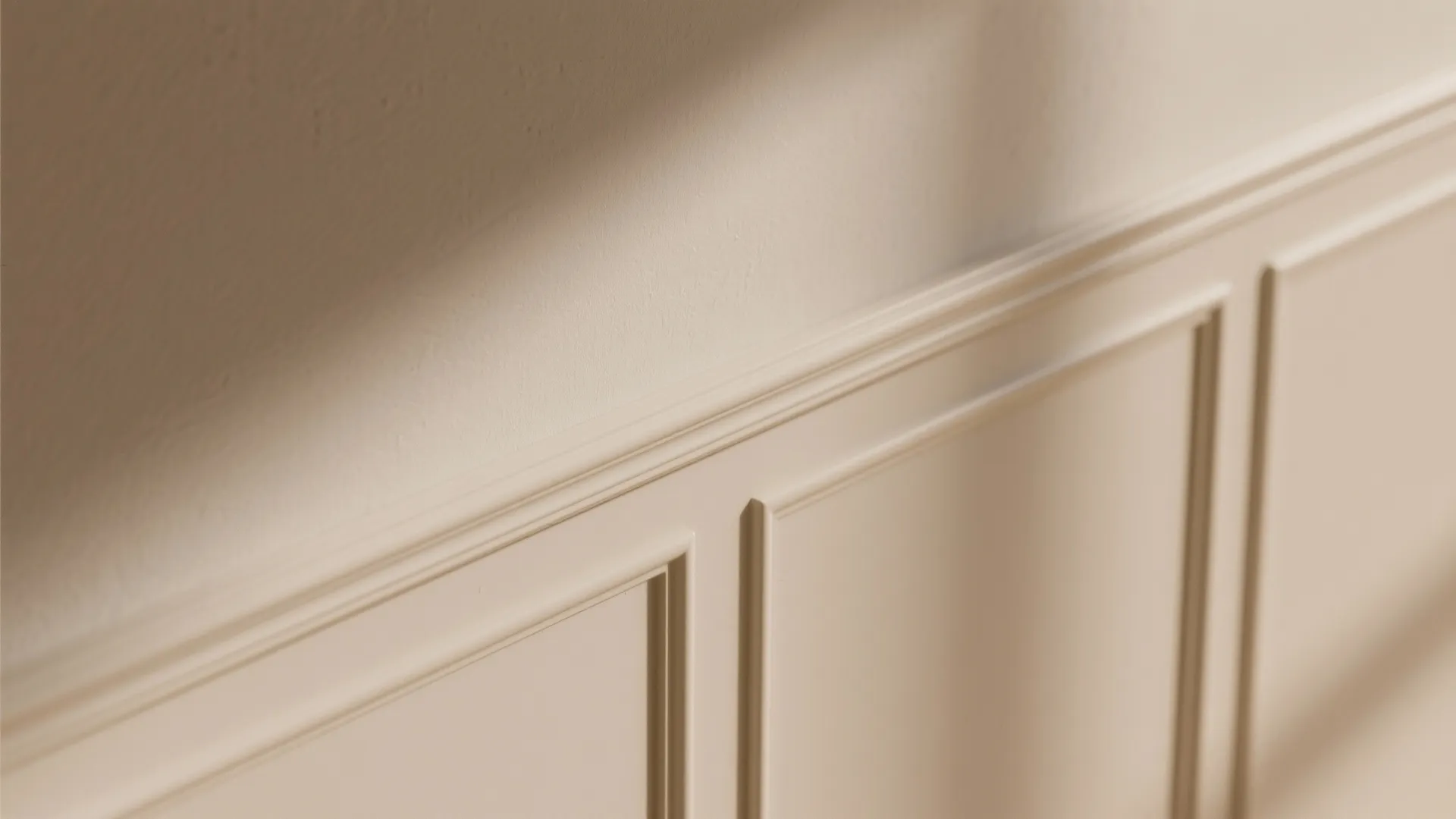 Cream colored wall panel with decorative molding showing light and shadow on a smooth surface