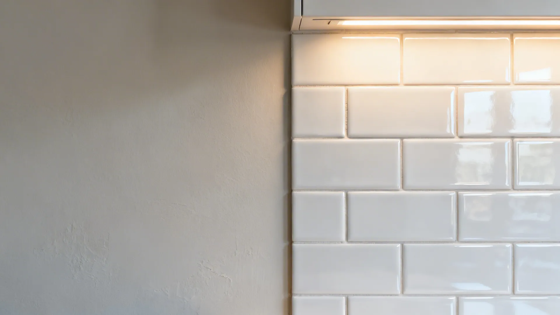 Split view showing a small kitchen wall before and after glossy subway tile installation.