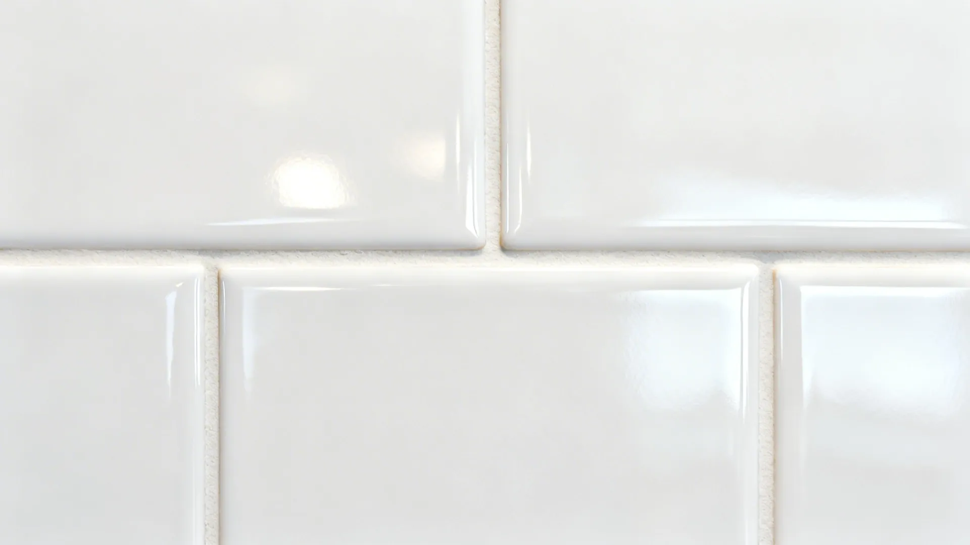Macro of glossy white subway tile with tight matched grout lines.