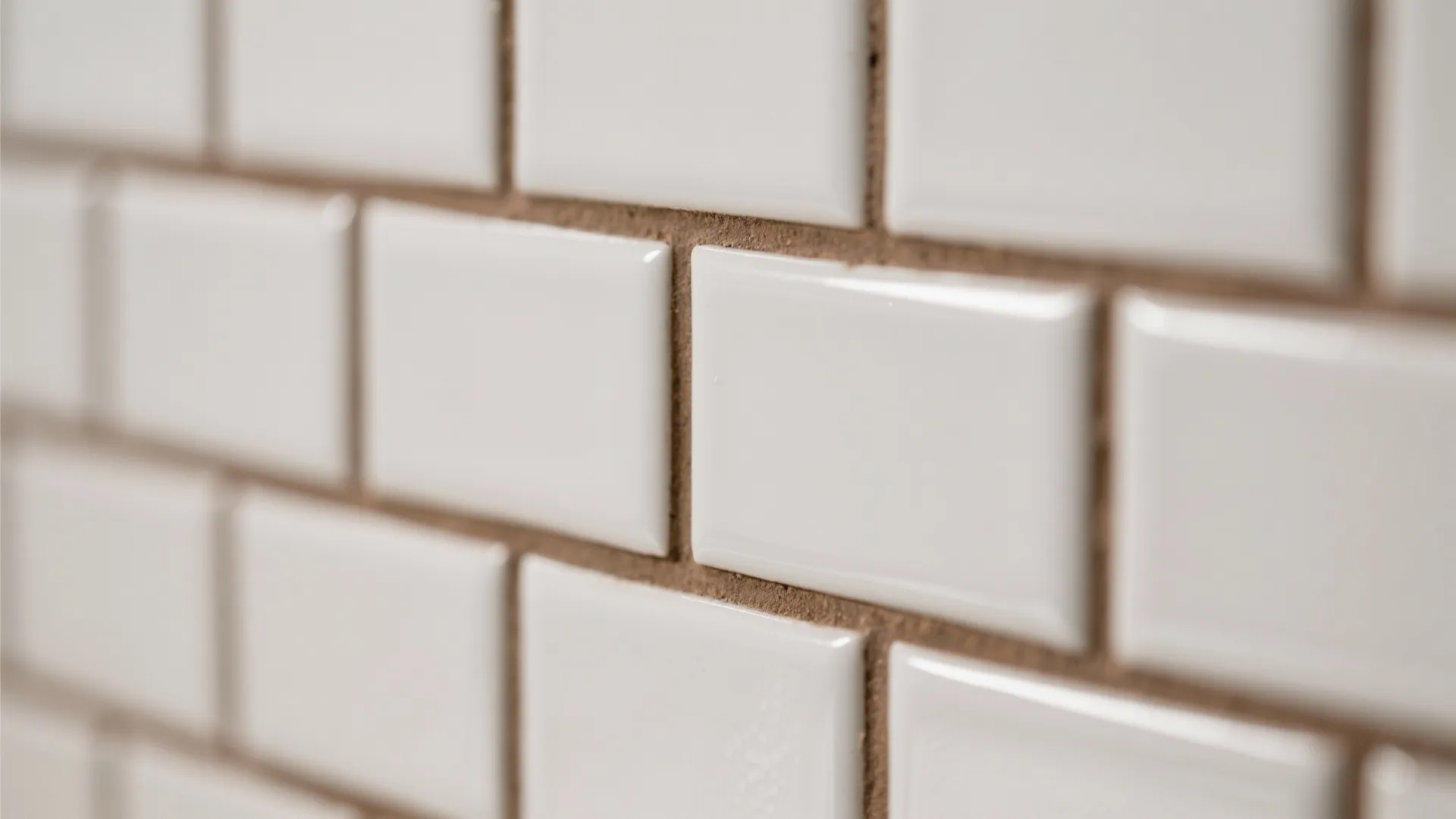 Macro of satin white subway tiles with mushroom grout showing subtle sheen and tight joints.