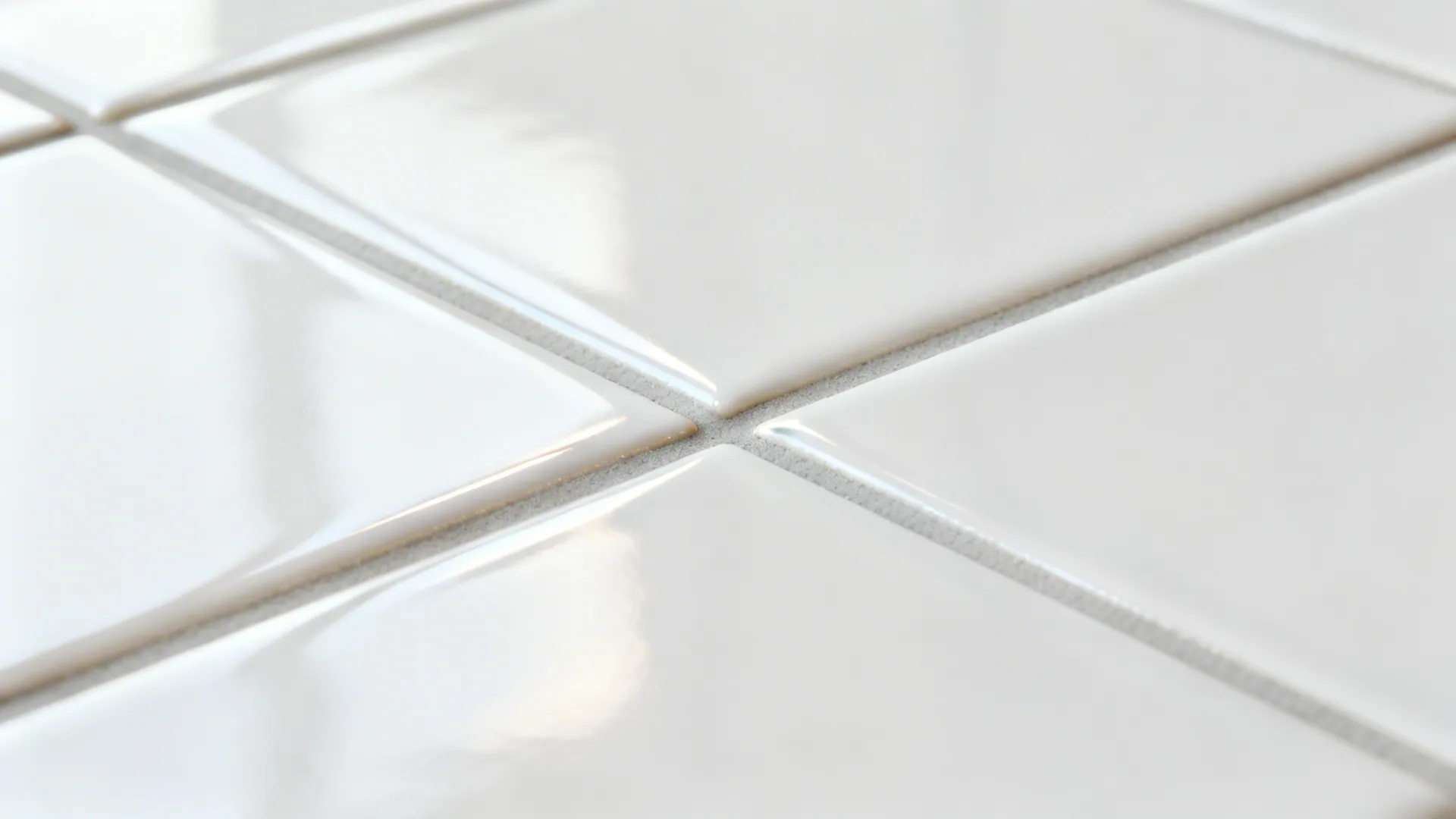 Macro of glossy subway tile with tight light gray epoxy grout.