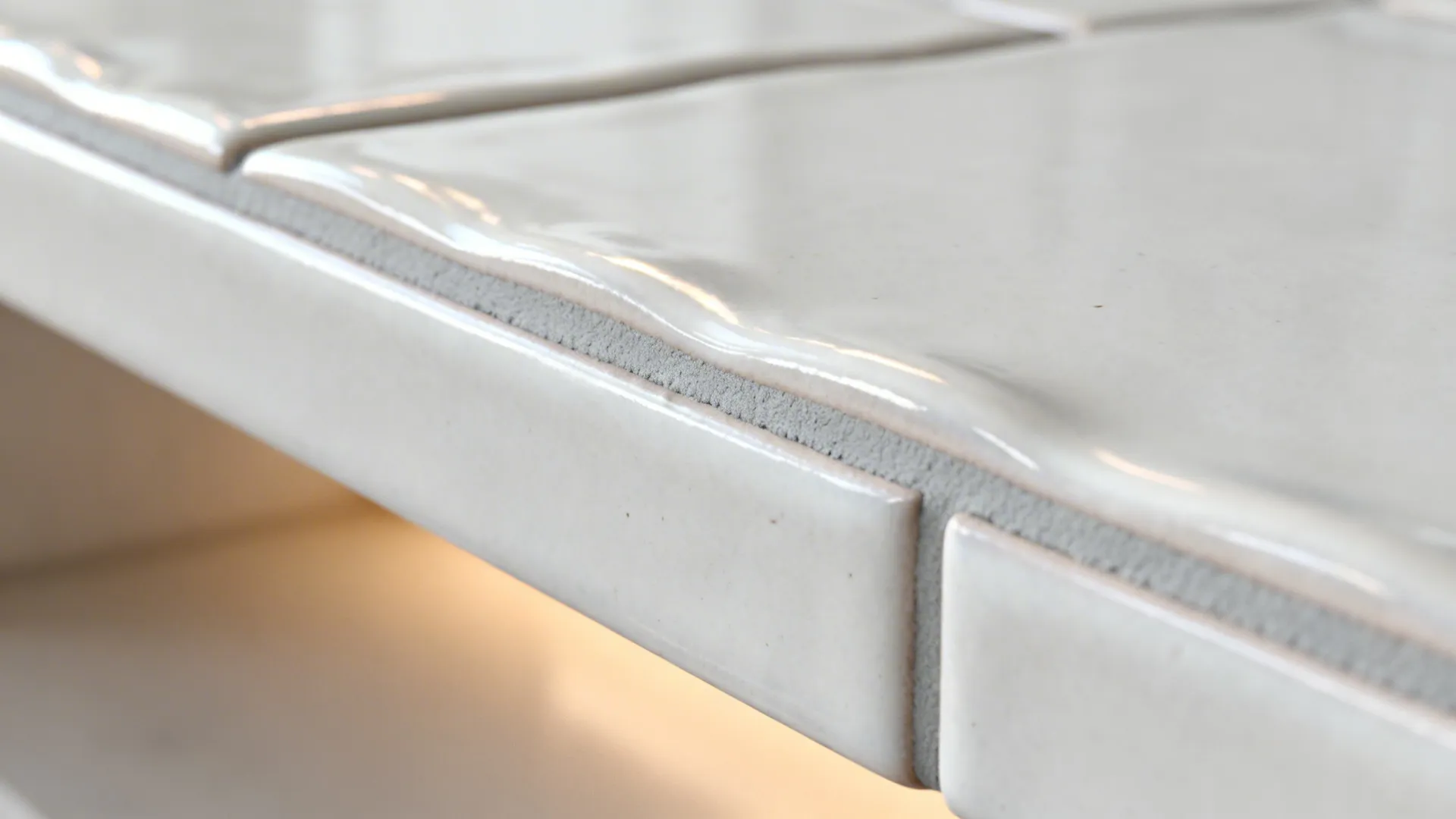 Close up view of glossy white wall tiles with grey grout showing a clean corner