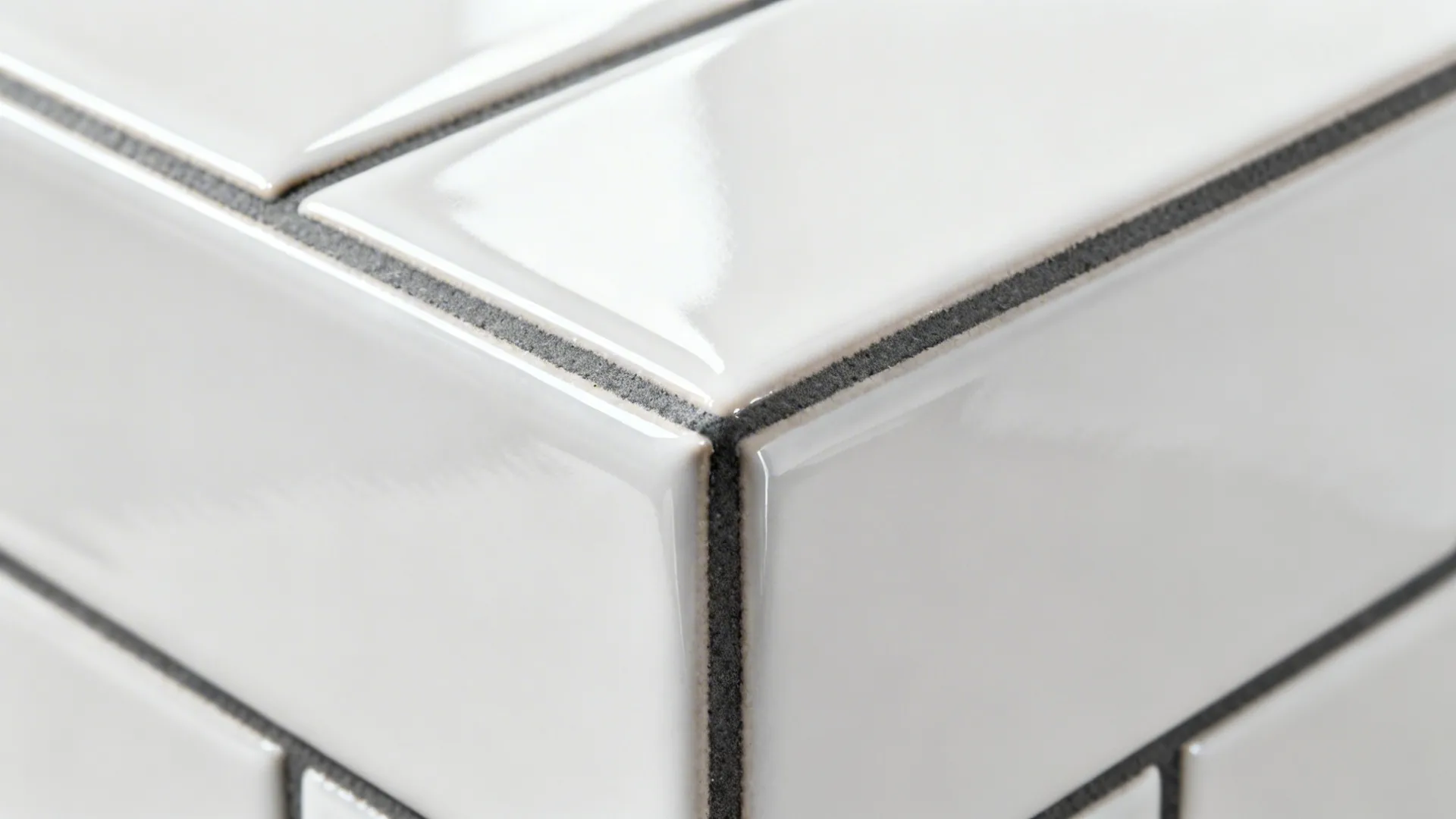 Close up of white glossy rectangular wall tiles with dark grey grout lines on a corner