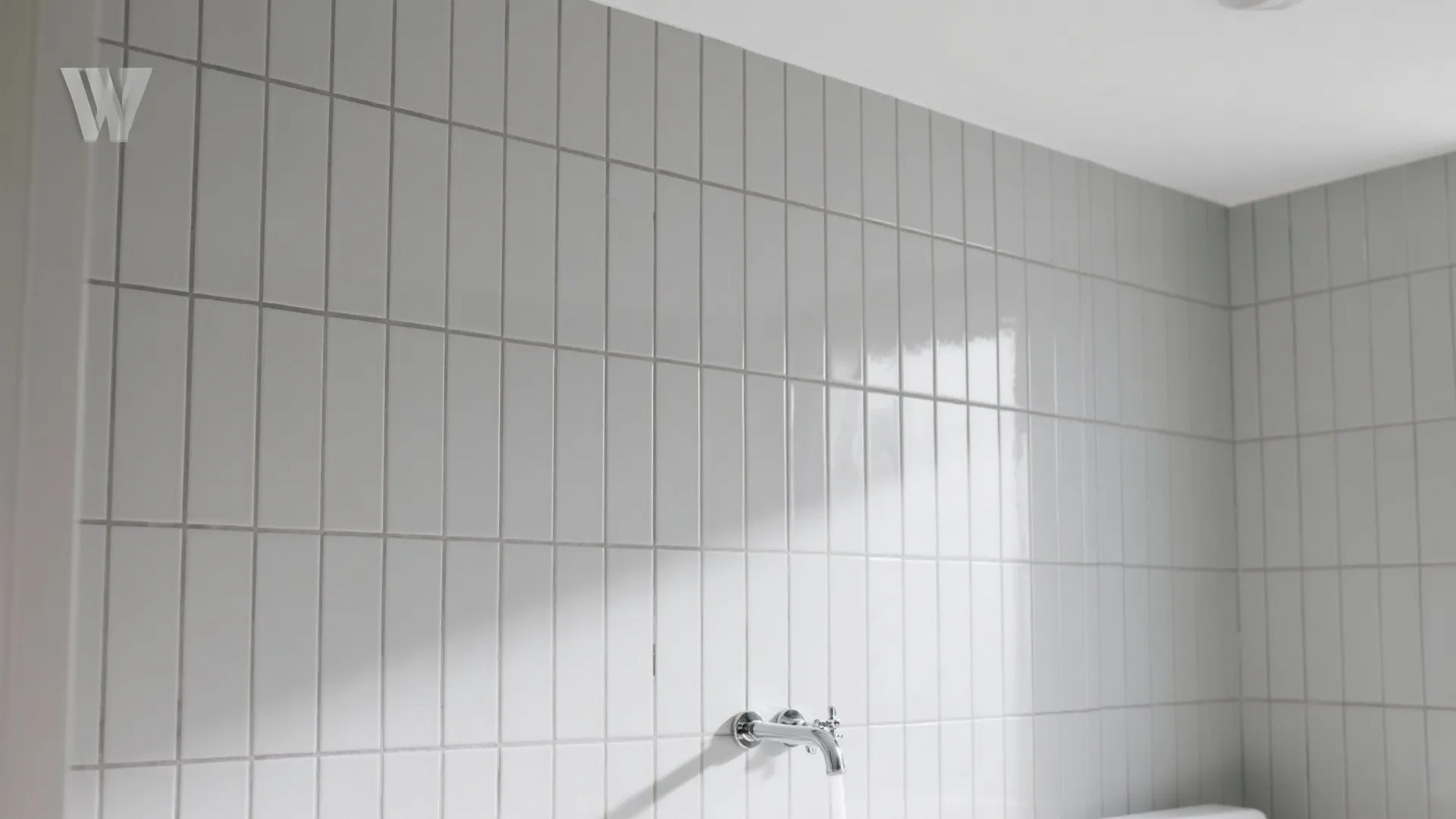 White vertical wall tiles in a bathroom or kitchen with a silver metal water tap