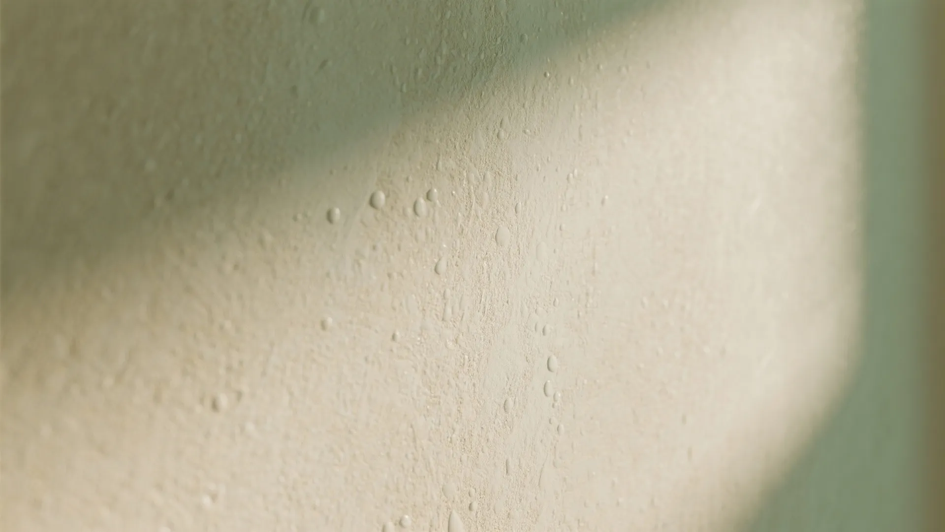 Close up view of cream colored wall texture with soft lighting and small water droplets detail