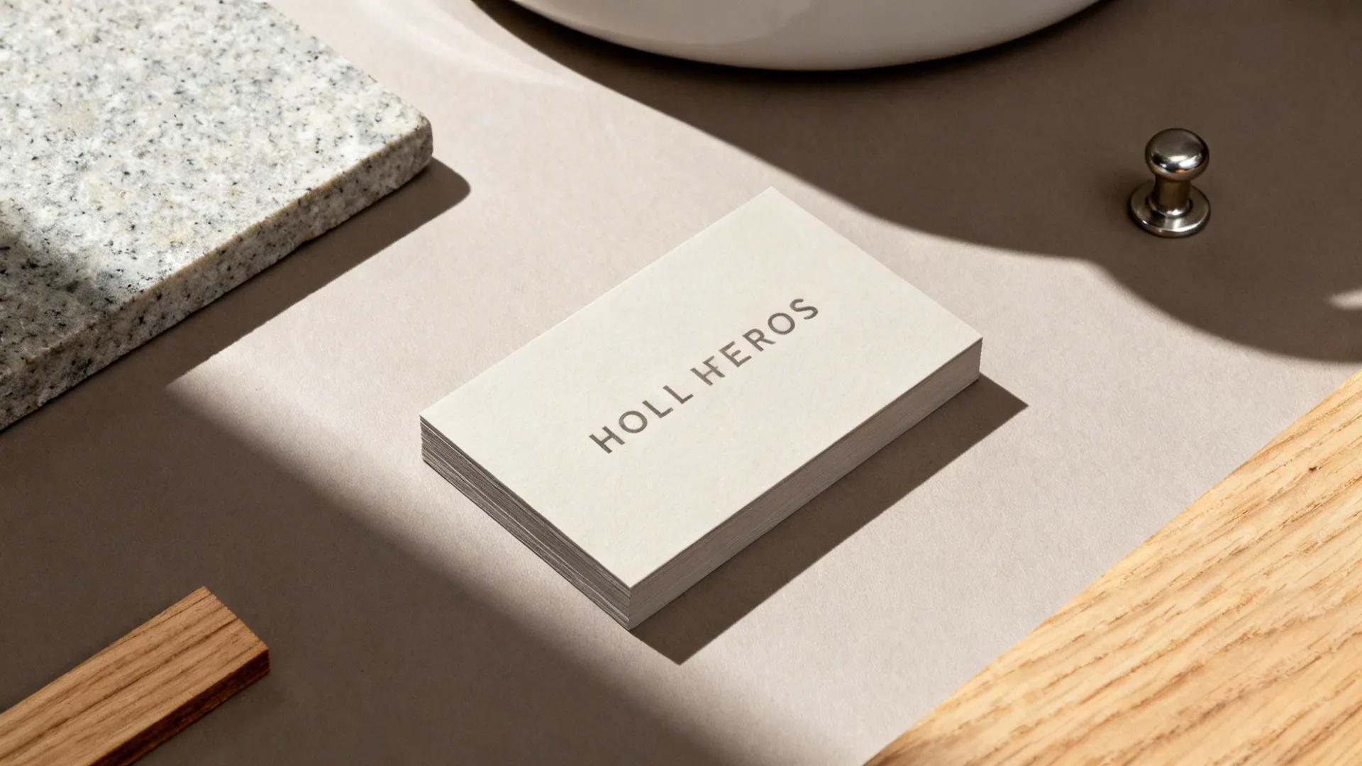 Stack of cream business cards on beige surface with grey stone block and natural wood pieces