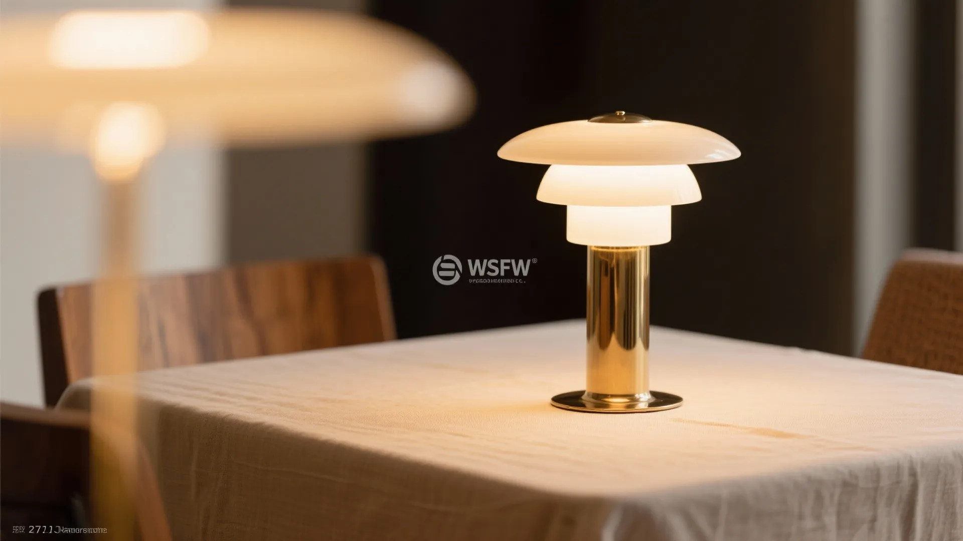Small white and gold table lamp sitting on a white tablecloth in a cozy room