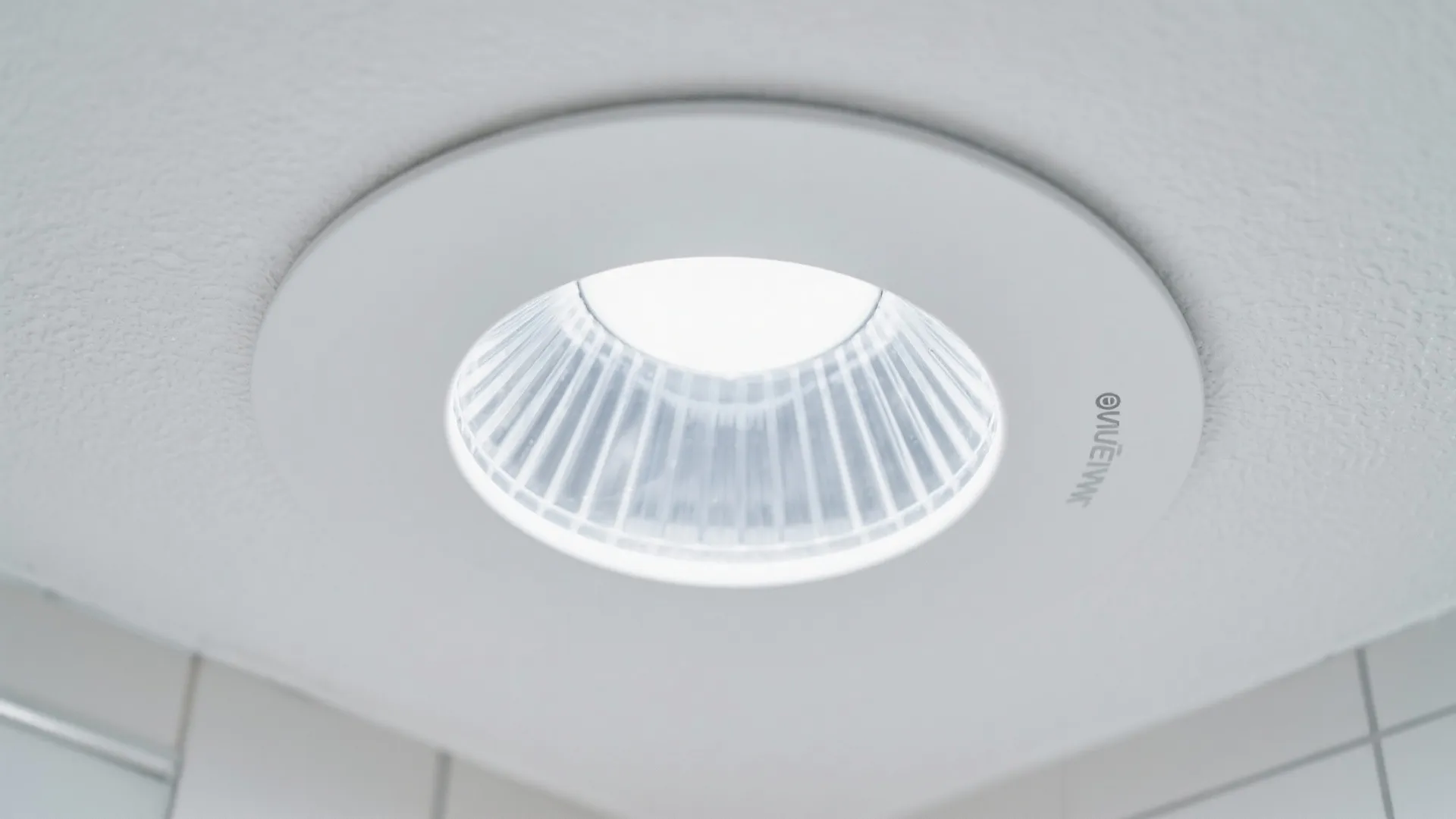 Close up view of a round white light fixture installed on a clean white ceiling