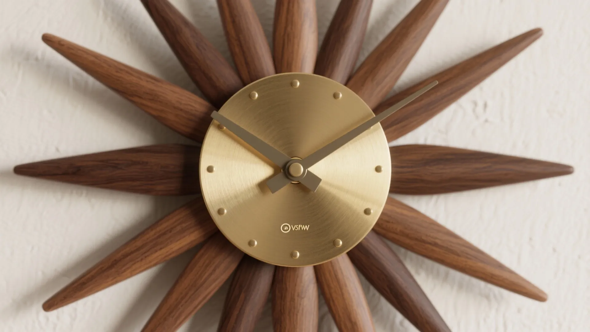 Macro detail of a mid-century sunburst clock with walnut rays and a brushed brass center on an off-white wall.