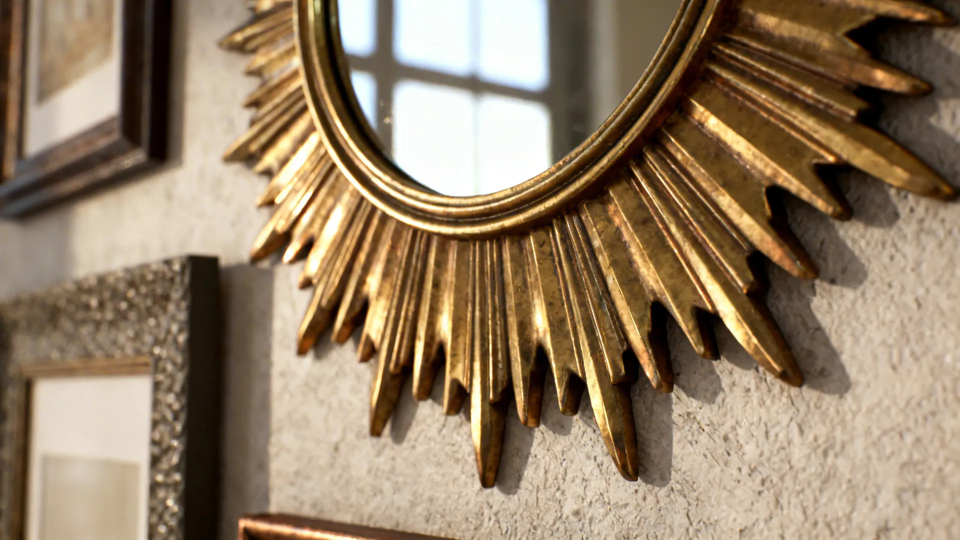 Close up of a gold sun shaped mirror hanging on a light colored textured wall