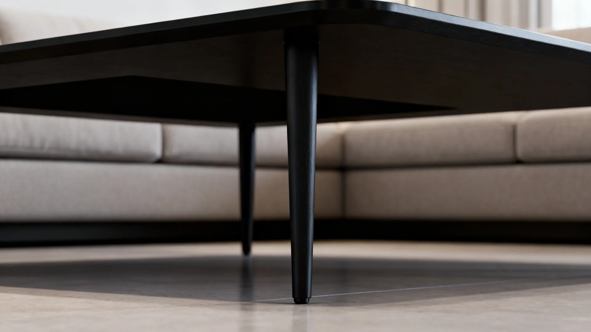 Close-up of raised slender legs on a black coffee table showing scale and airiness