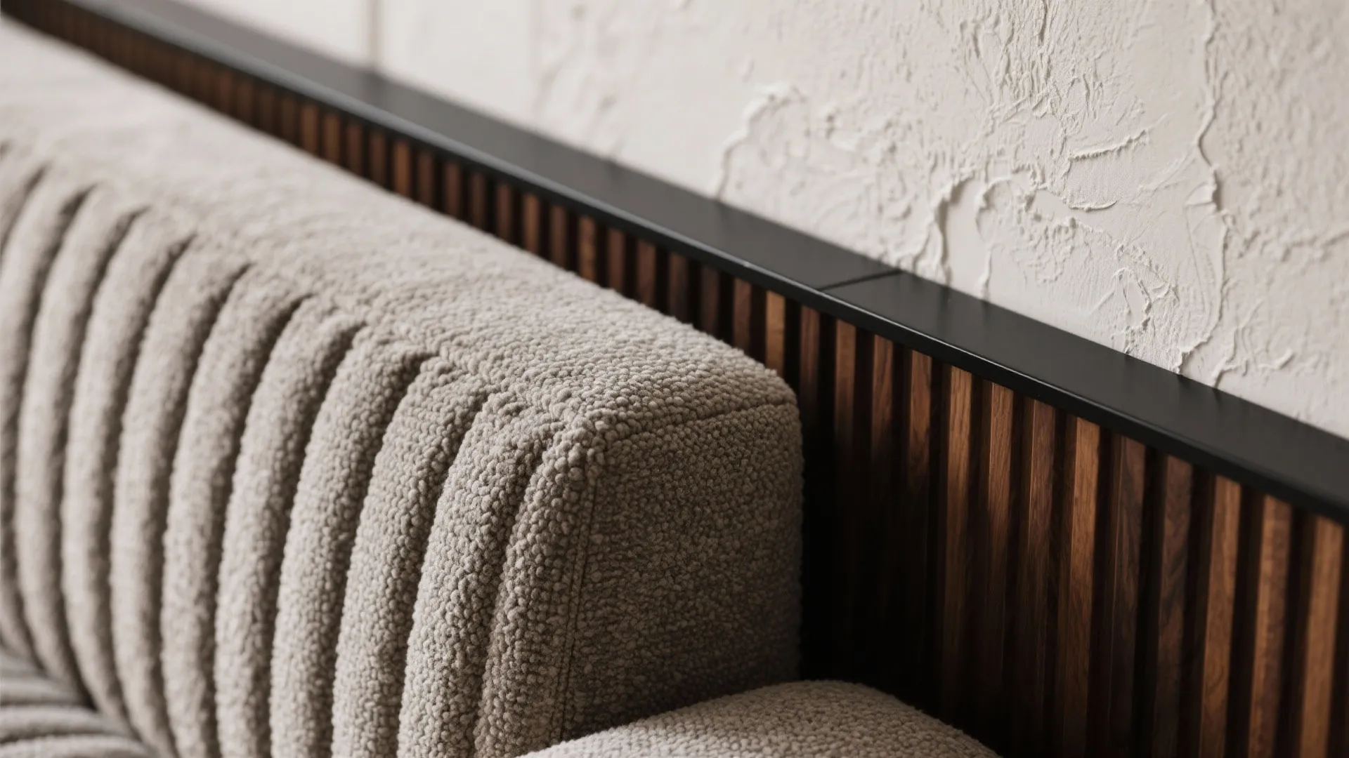 Close up of a textured fabric sofa against a dark wood wall panel and plaster