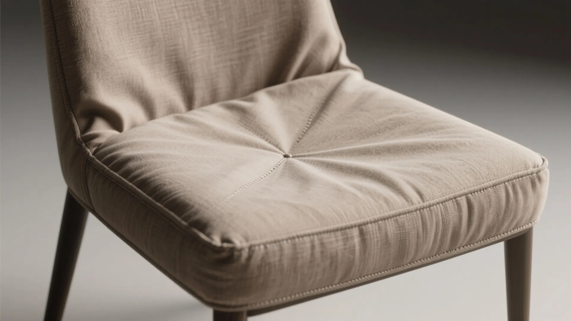 Close up of a beige fabric chair showing detailed texture with a single center button