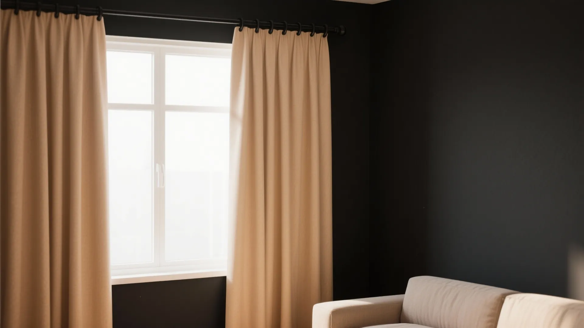 Tan curtain hanging on a black rod next to a white window and dark wall