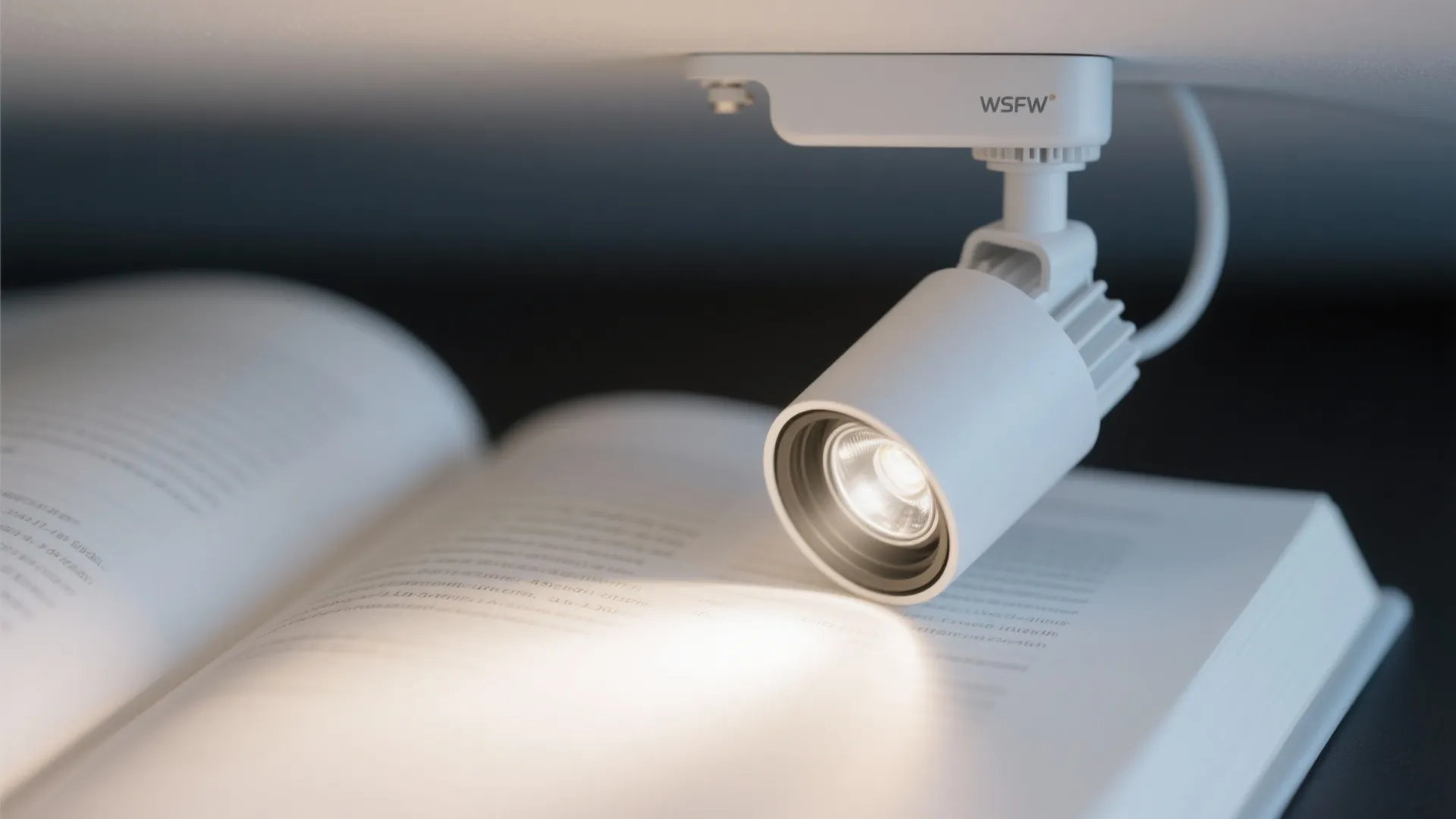 Adjustable ceiling spotlight with a clean beam aimed across a book page.
