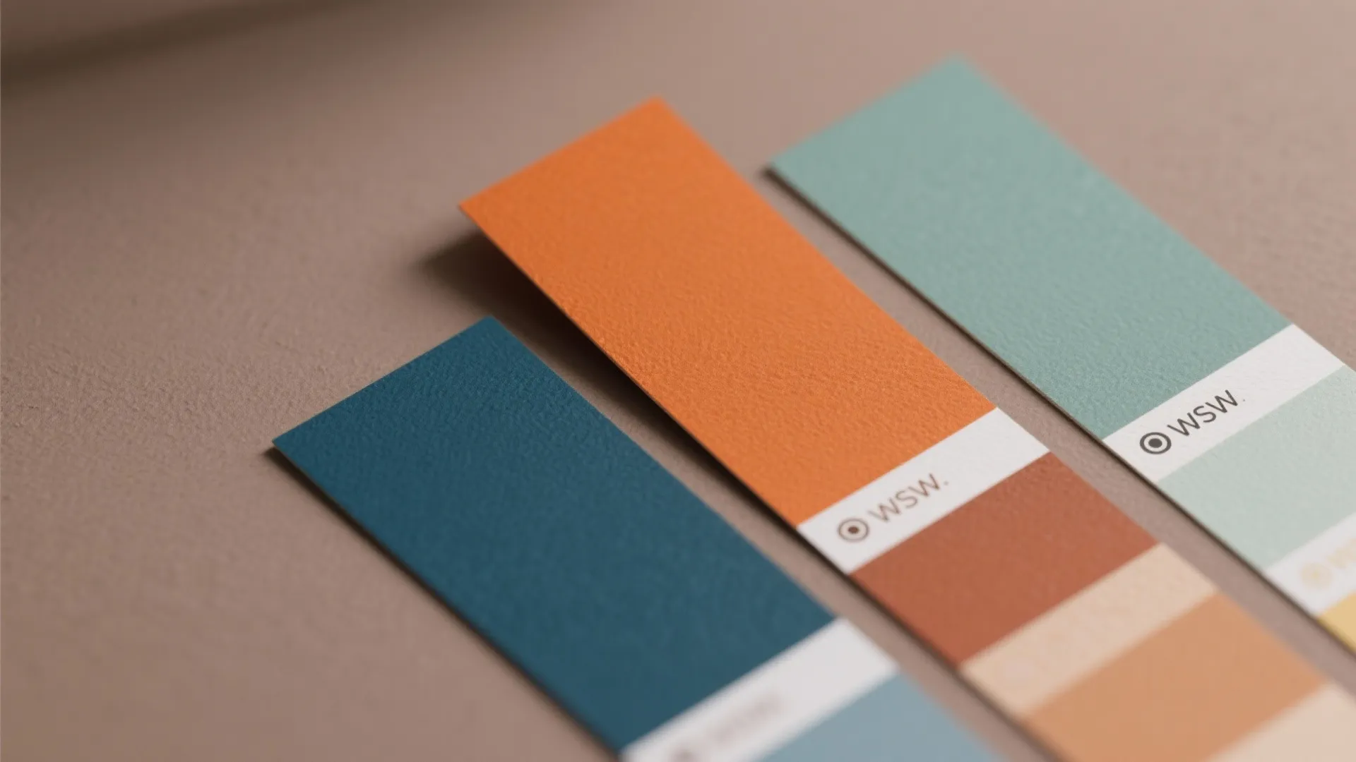 Three colorful paint swatch cards showing blue, orange, and green shades for interior design planning