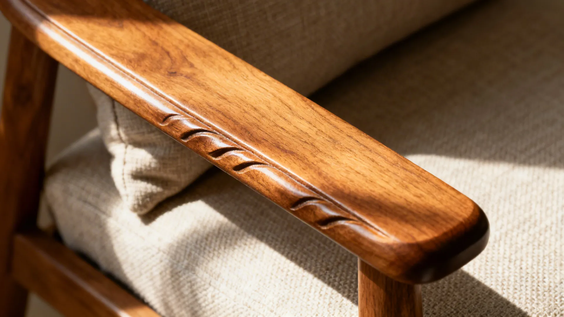 Macro of a carved mid-tone teak sofa arm beside a textured neutral linen cushion.