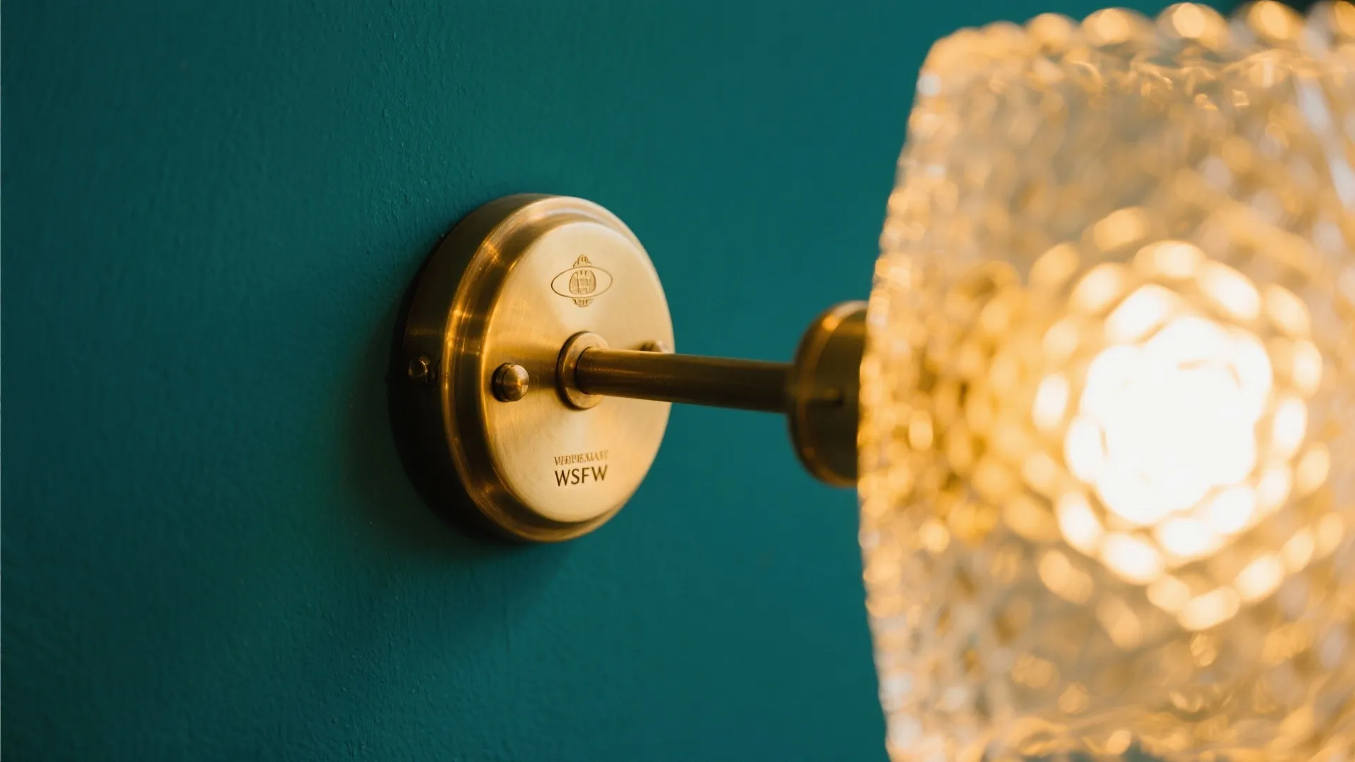 Brass light fixture glowing against teal wall