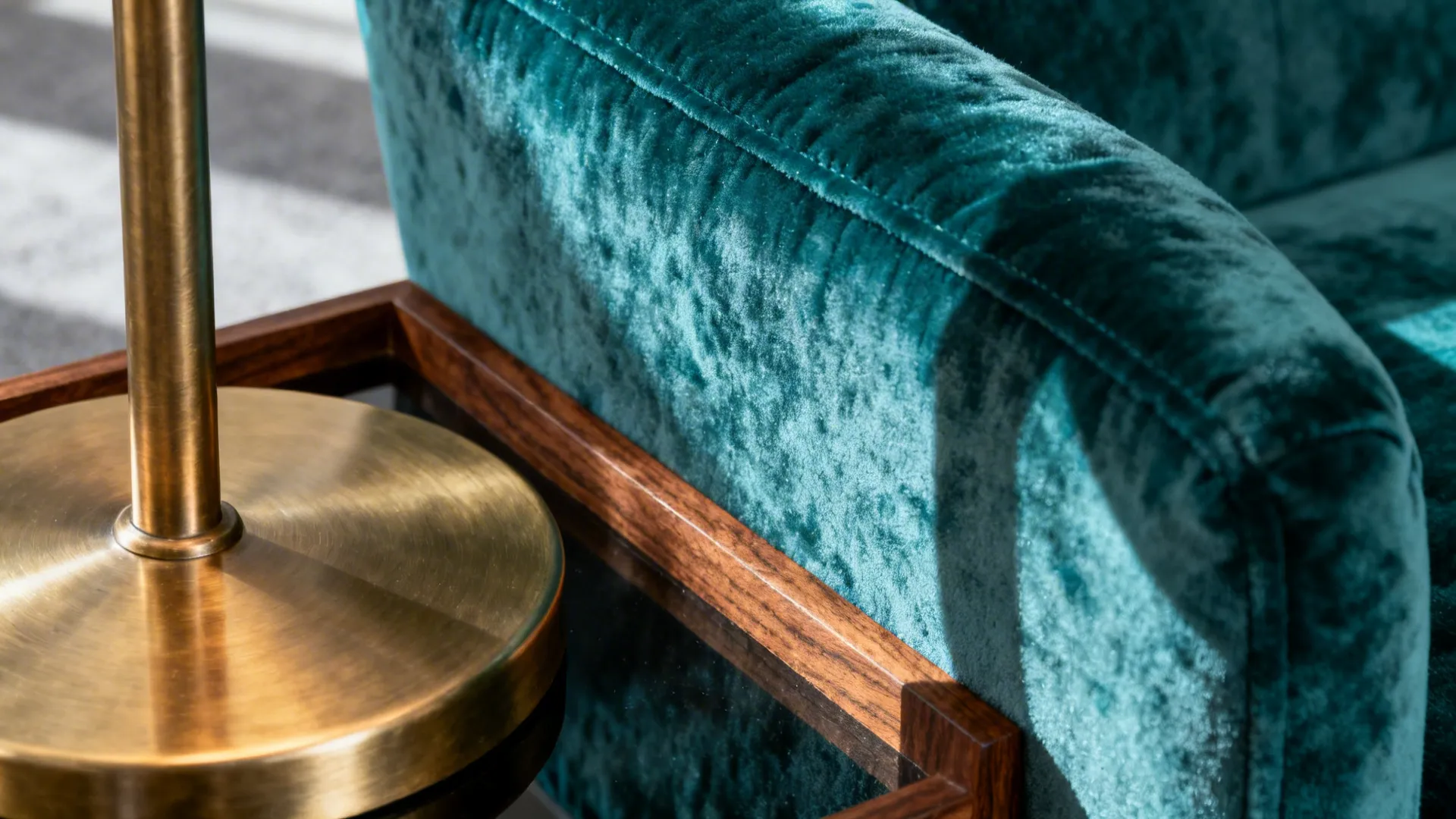 Close-up of teal velvet with brushed brass and walnut accents showing rich texture and warmth.