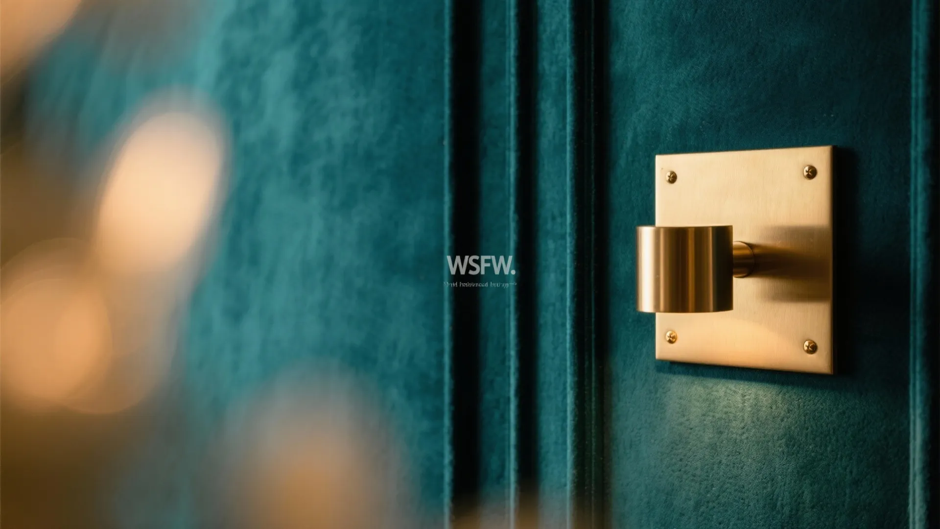 Close up of a gold wall light fixture on a dark teal textured wall panel