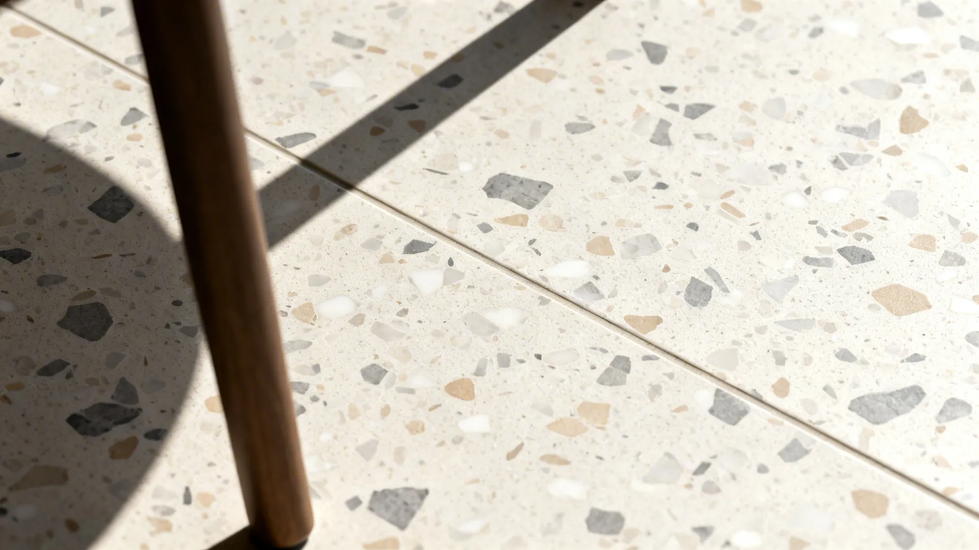 Macro of fine-chip terrazzo-look porcelain in neutral tones with a matte finish.