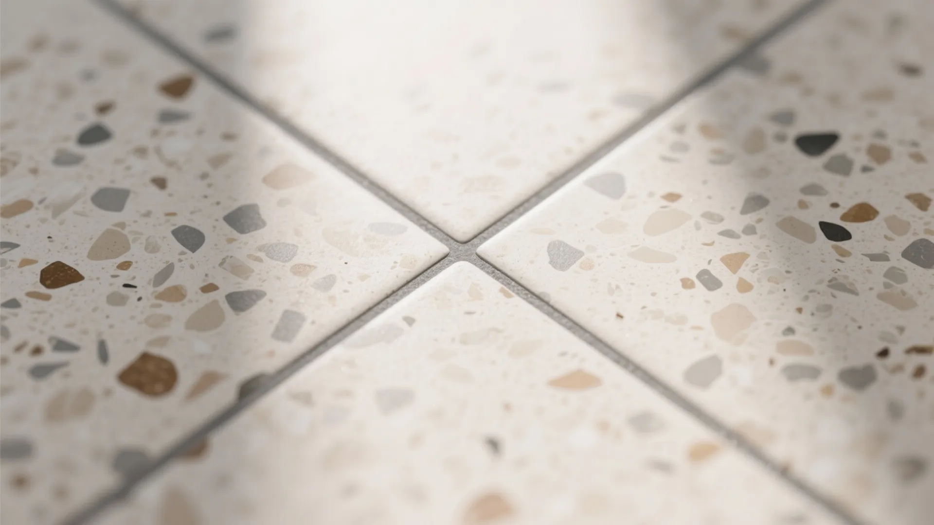 Close up view of floor tiles with small colorful stone pieces and gray grout lines