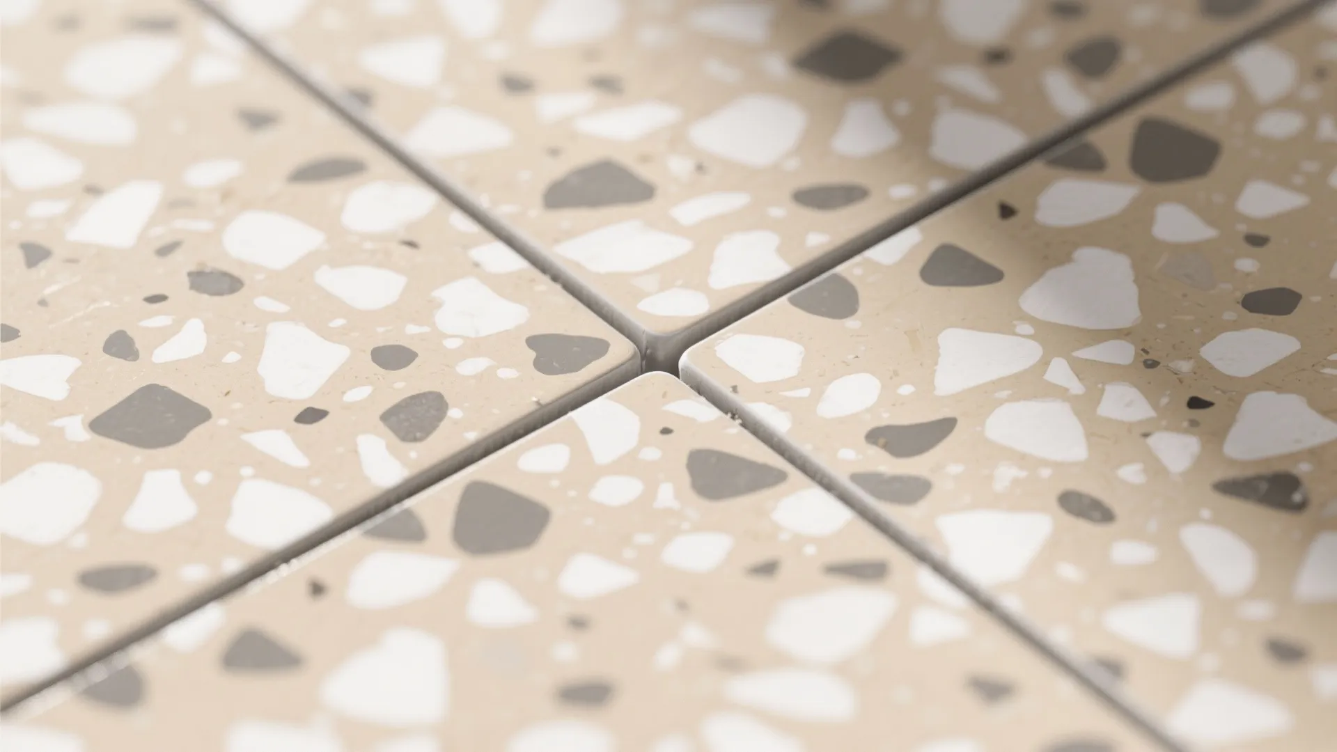 Close up view of four square floor tiles with beige, grey, and white stone patterns