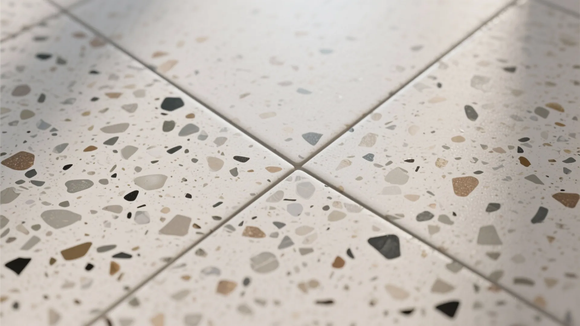 Macro of matte terrazzo-look porcelain with subtle speckles and thin color-matched grout.