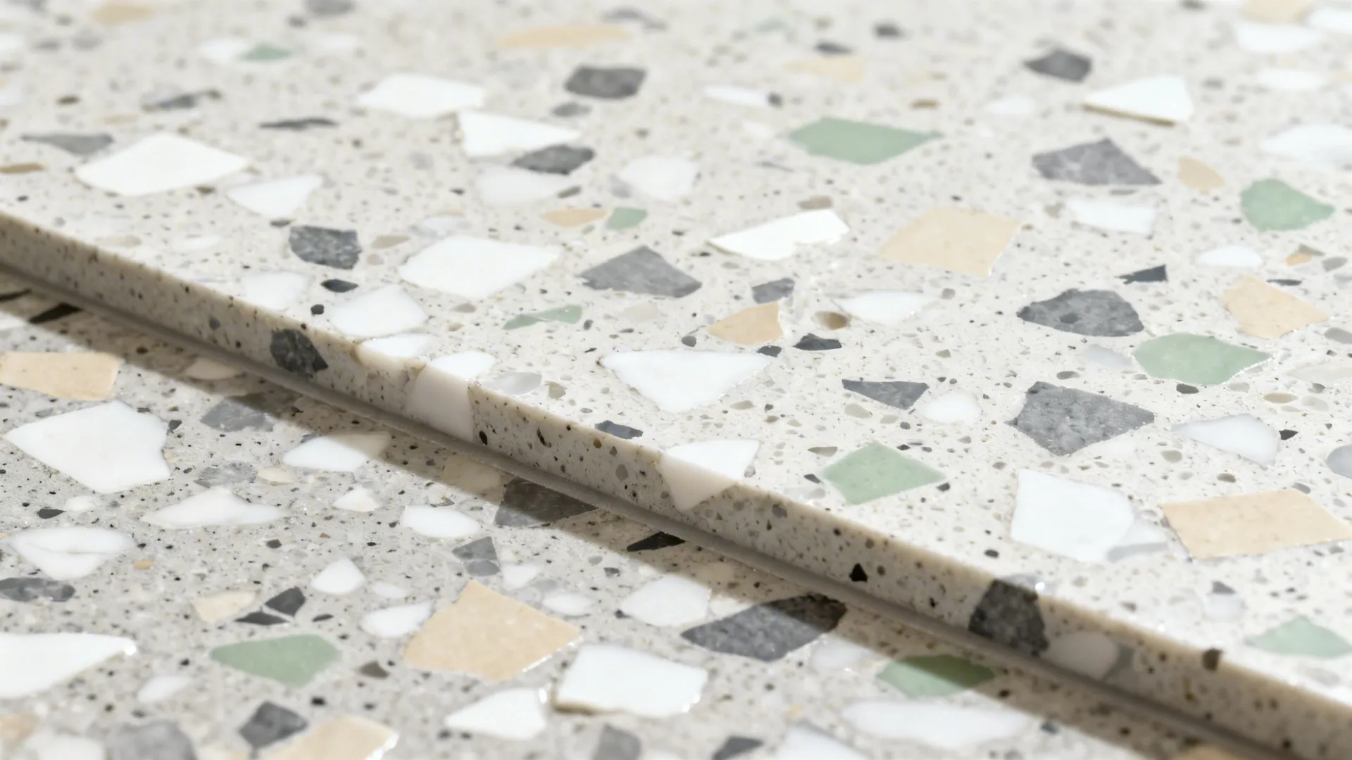 Macro of terrazzo floor with multicolor chips in a mid-tone cement matrix under soft daylight.