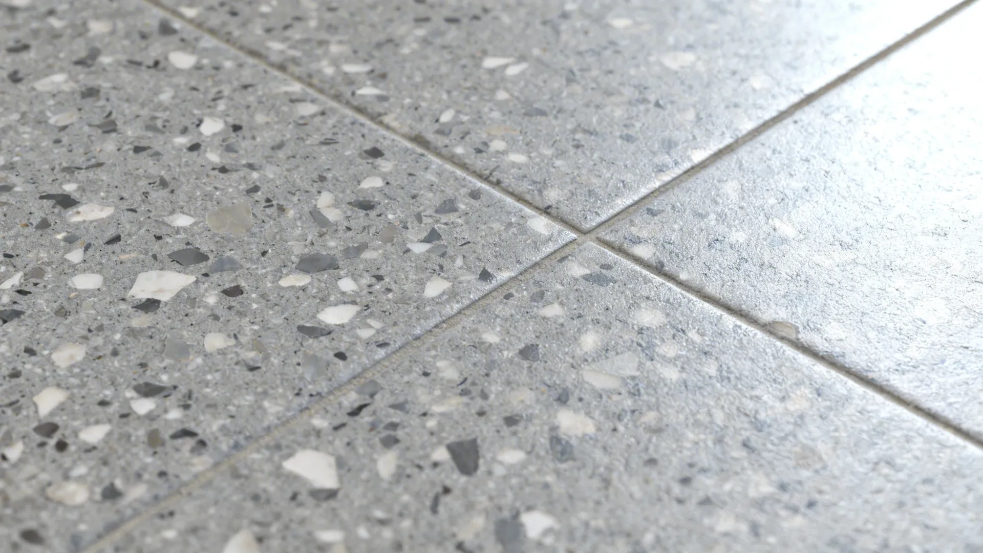 Macro of fine-aggregate terrazzo-look porcelain with tone-matched grout in cool gray.