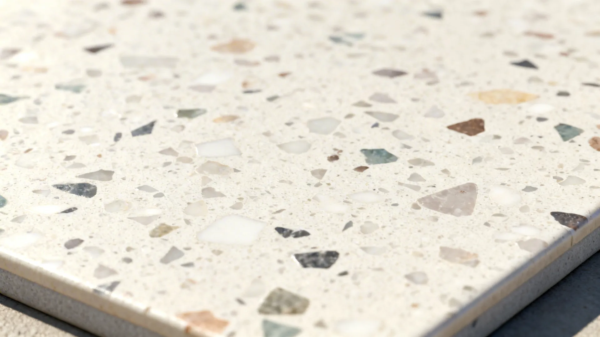 Close up of white floor tile with small colorful stone pieces scattered across the polished surface