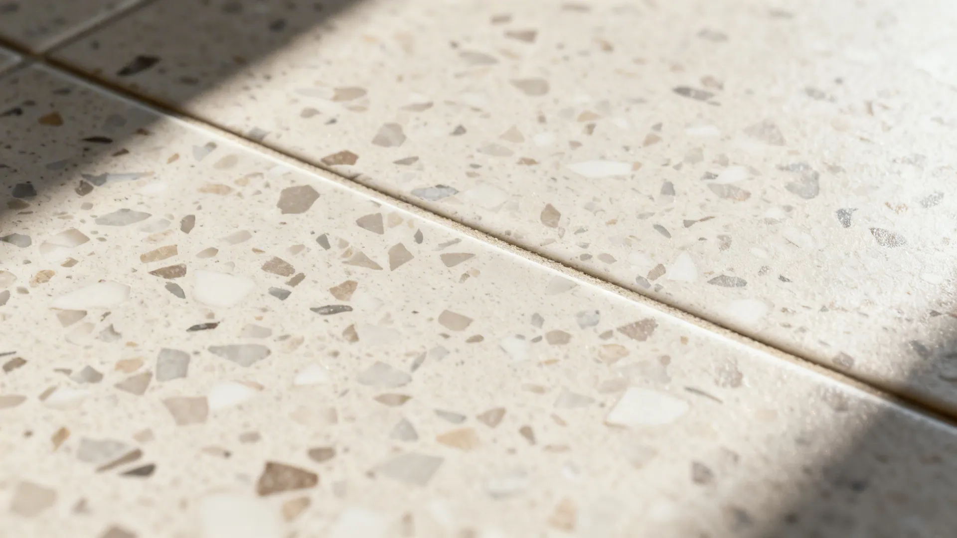 Close up view of light beige terrazzo floor tiles with small brown and grey spots