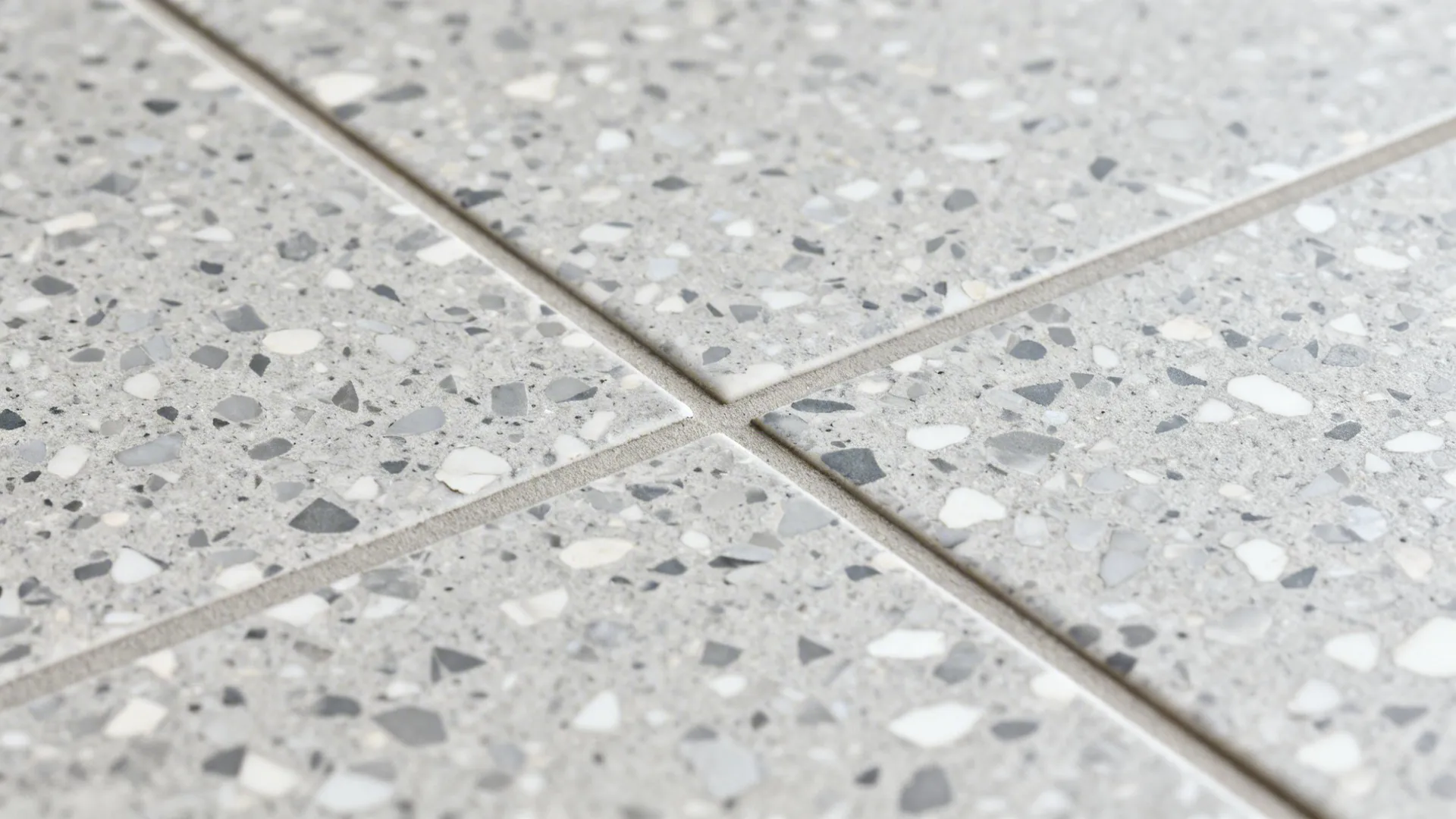 Macro of fine-chip grey terrazzo-look porcelain tile with matching grout.