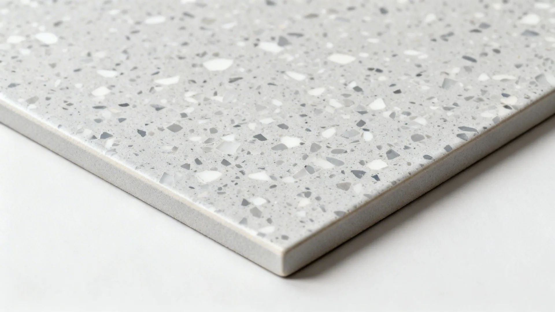 Macro detail of light gray terrazzo-look porcelain with fine speckles and tight grout.