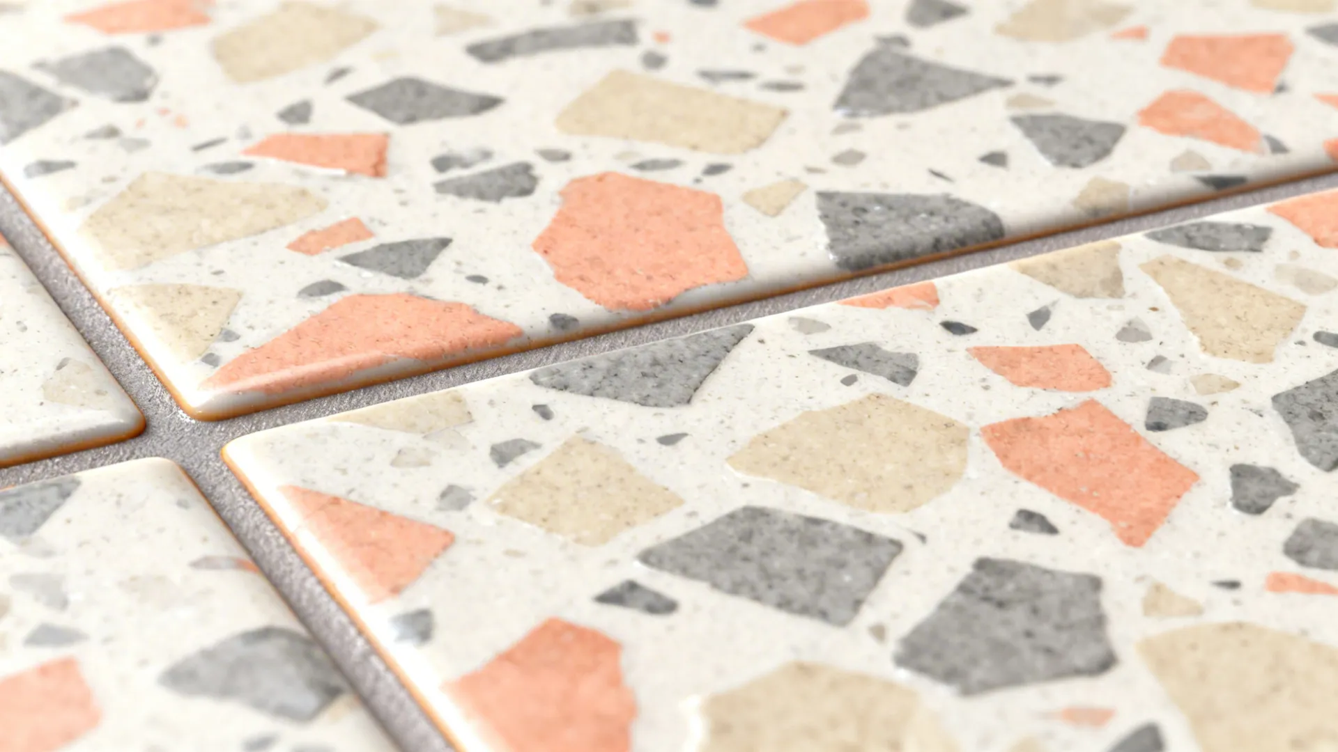 Macro of terrazzo-look tile with warm coral and sand chips and satin glaze.