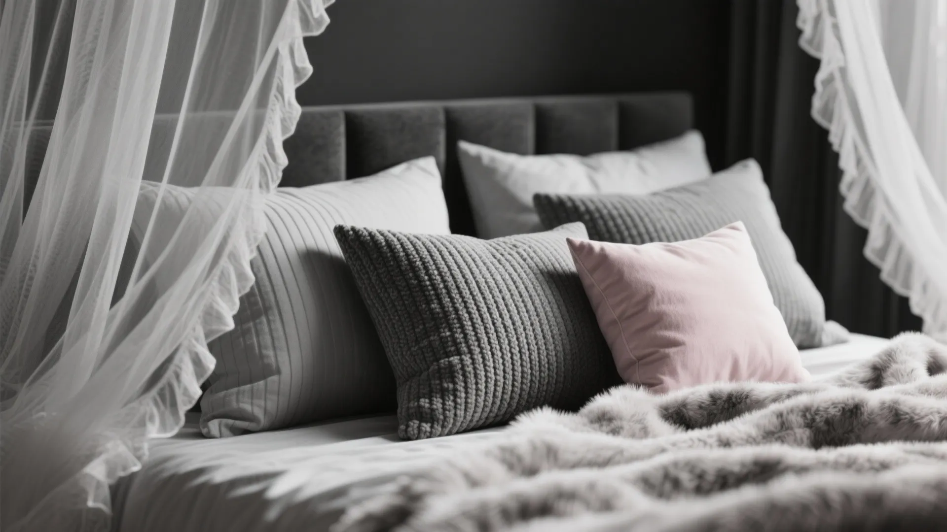 Close-up of black-and-white bedding layers with faux fur, ribbed pillows and a blush accent cushion.