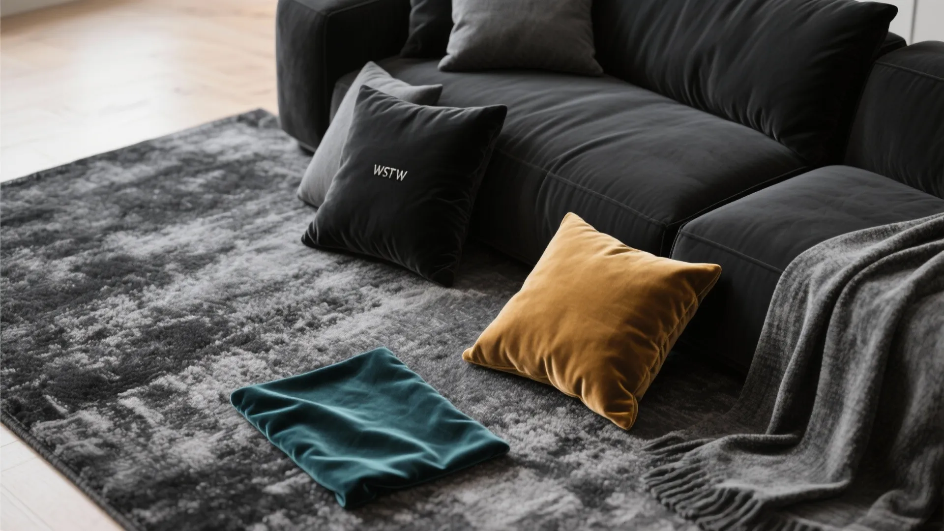 Close up of a grey sofa with colored pillows on a textured rug and blanket