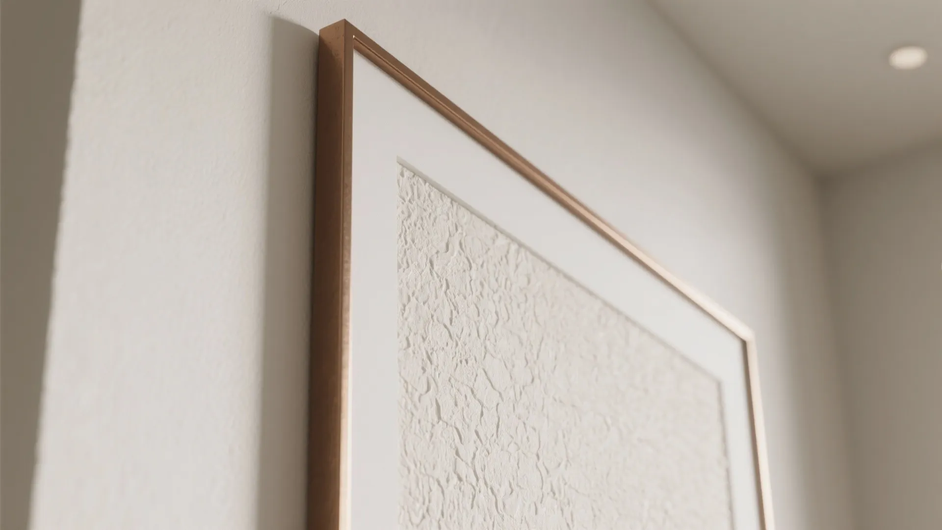 Macro detail of textured wall panel and slim-framed artwork with soft grazing light.