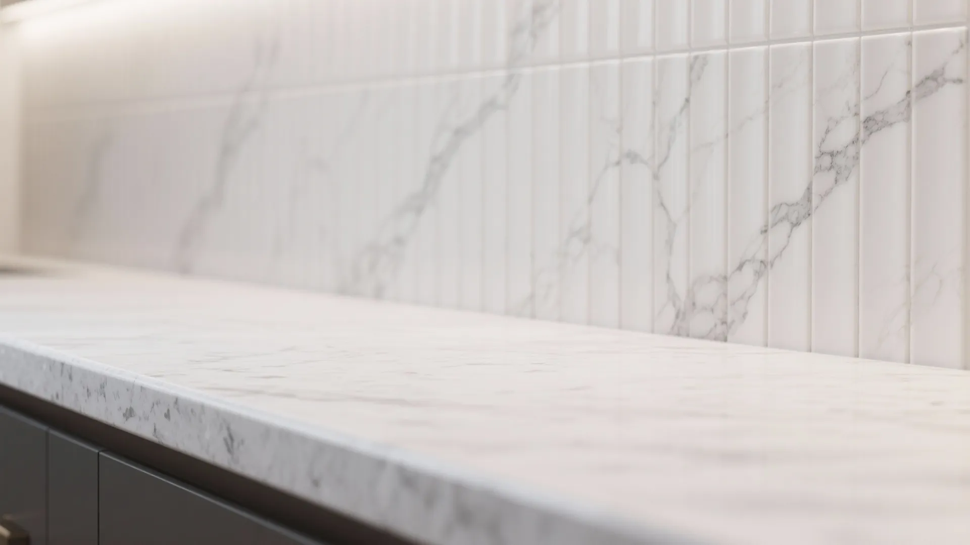 Detail of honed white granite meeting a textured fluted tile backsplash.