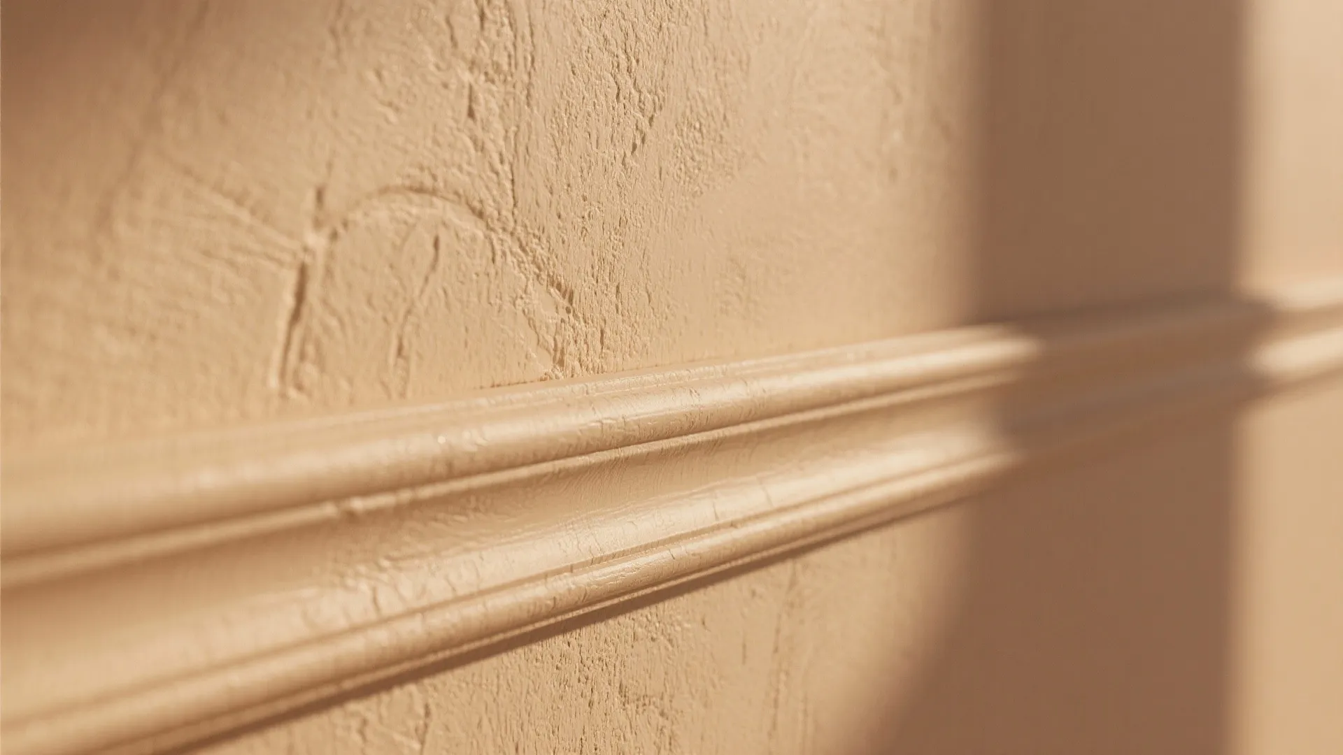 Close-up of matte tan painted wall with satin trim, showing plaster texture and subtle finish contrast.