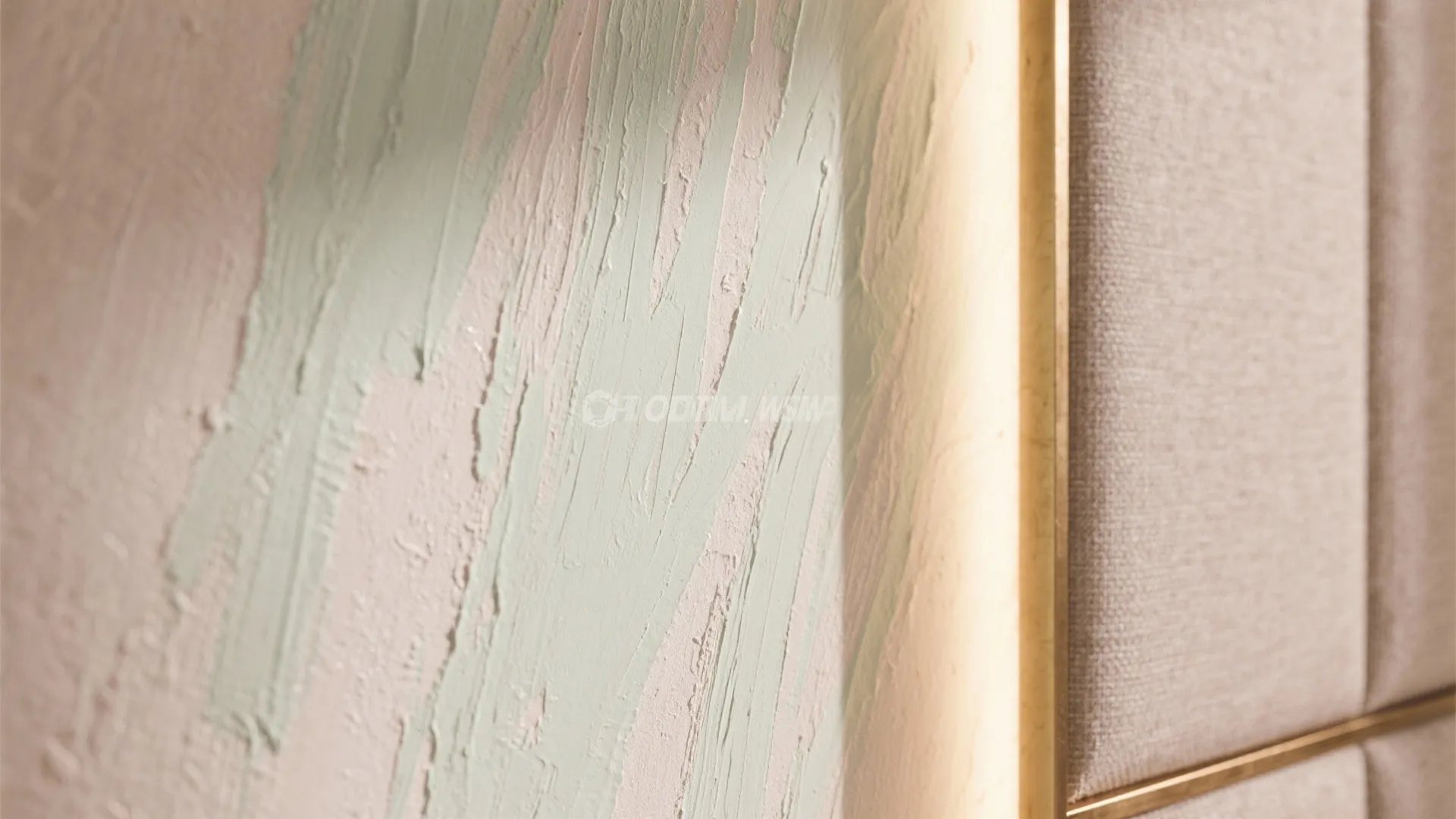 Close up of light green paint strokes on textured wall with warm glow from lighting