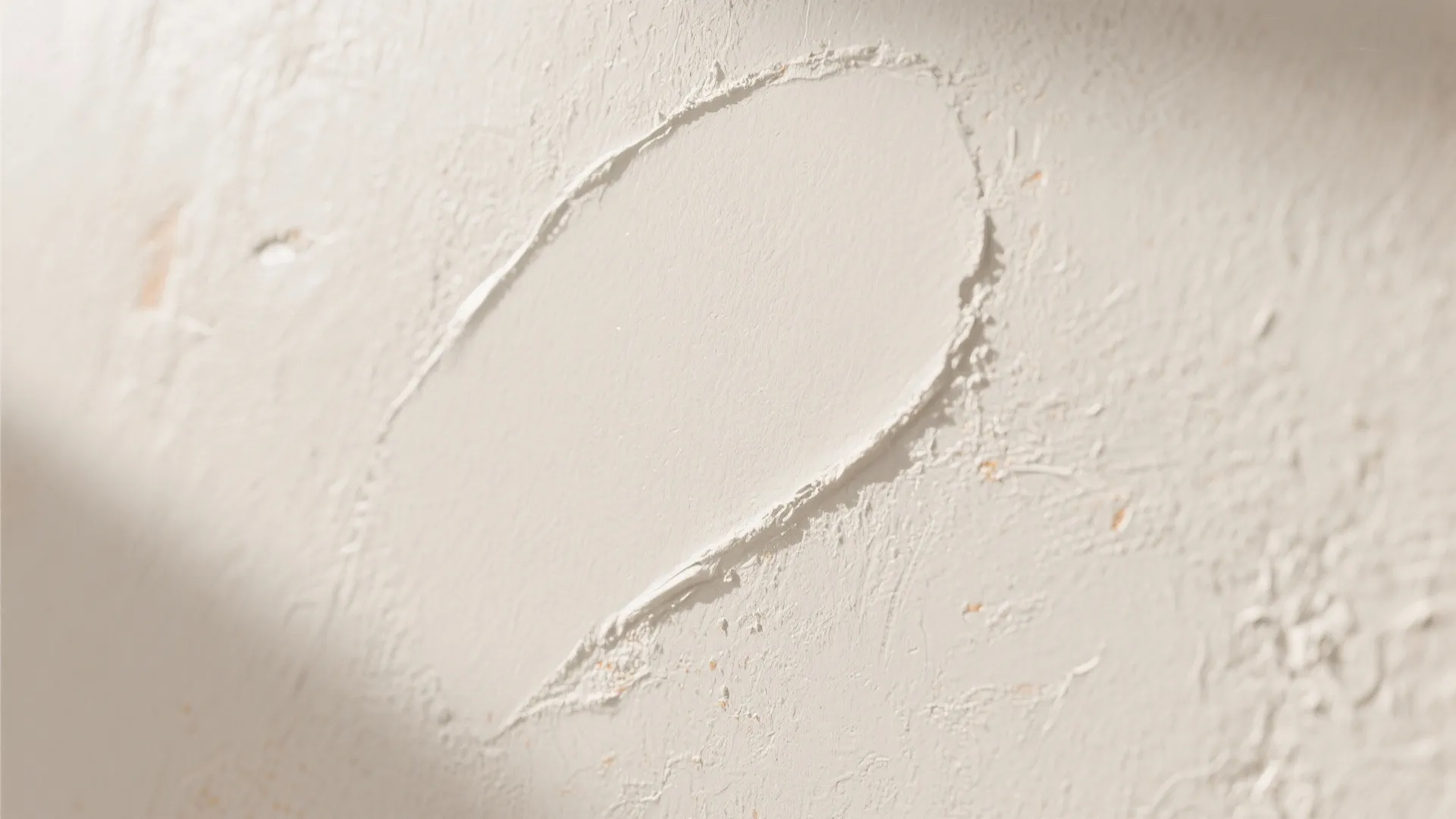 Close up view of white textured wall paint showing a smooth stroke of wet plaster