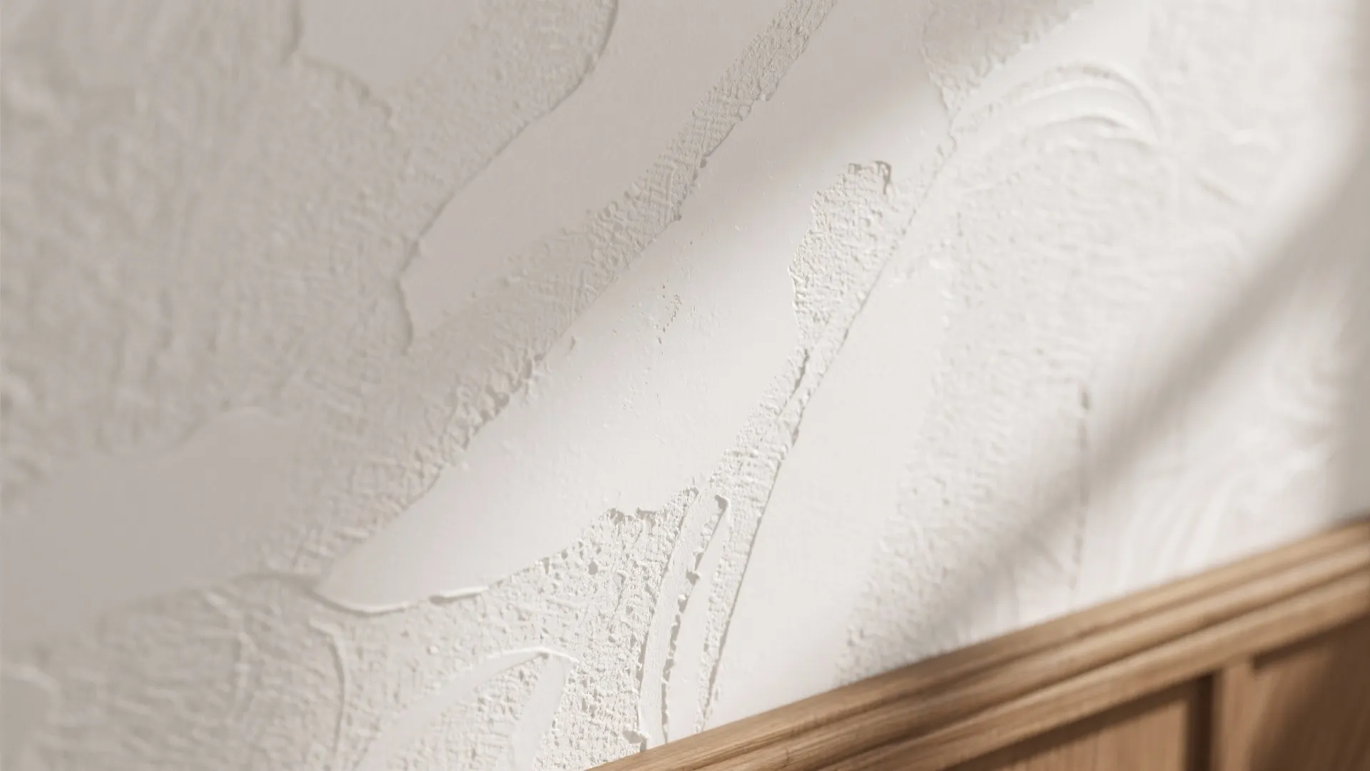 Macro detail of white plaster-look wallpaper with raking light that reveals rich embossing.