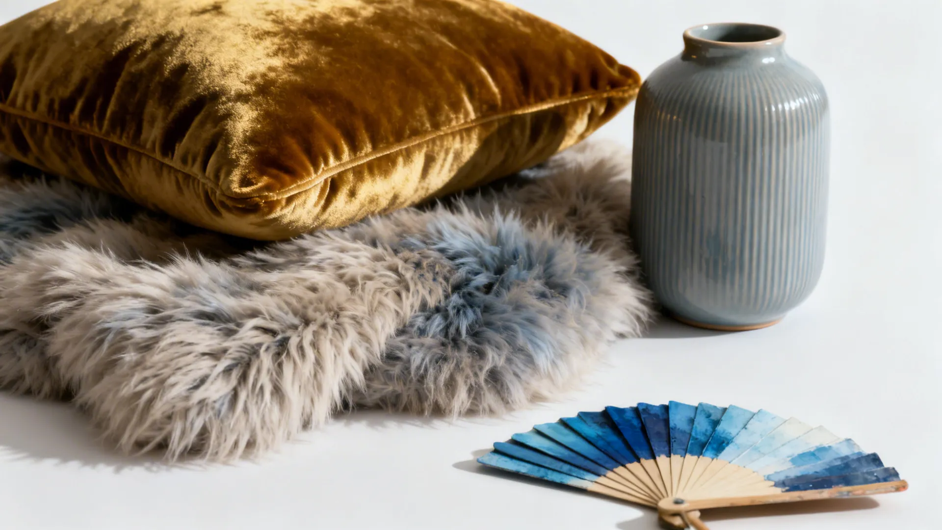 Texture samples including velvet cushion, faux-sheepskin, and ribbed ceramic vase for blue-and-silver schemes.
