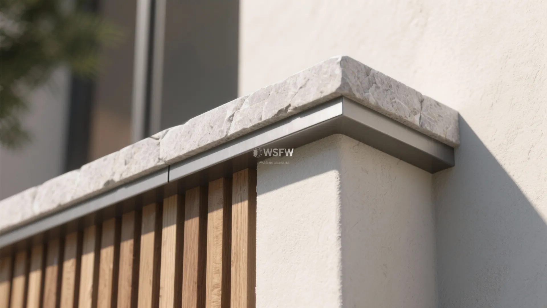 Close up of a stone wall top with metal trim and vertical wood wall panel