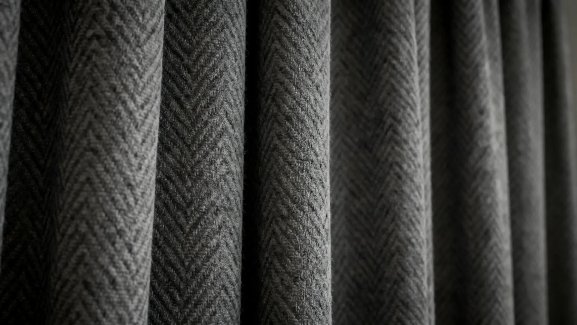 Close-up of patterned dark grey curtain fabric showing chevron and slub textures.